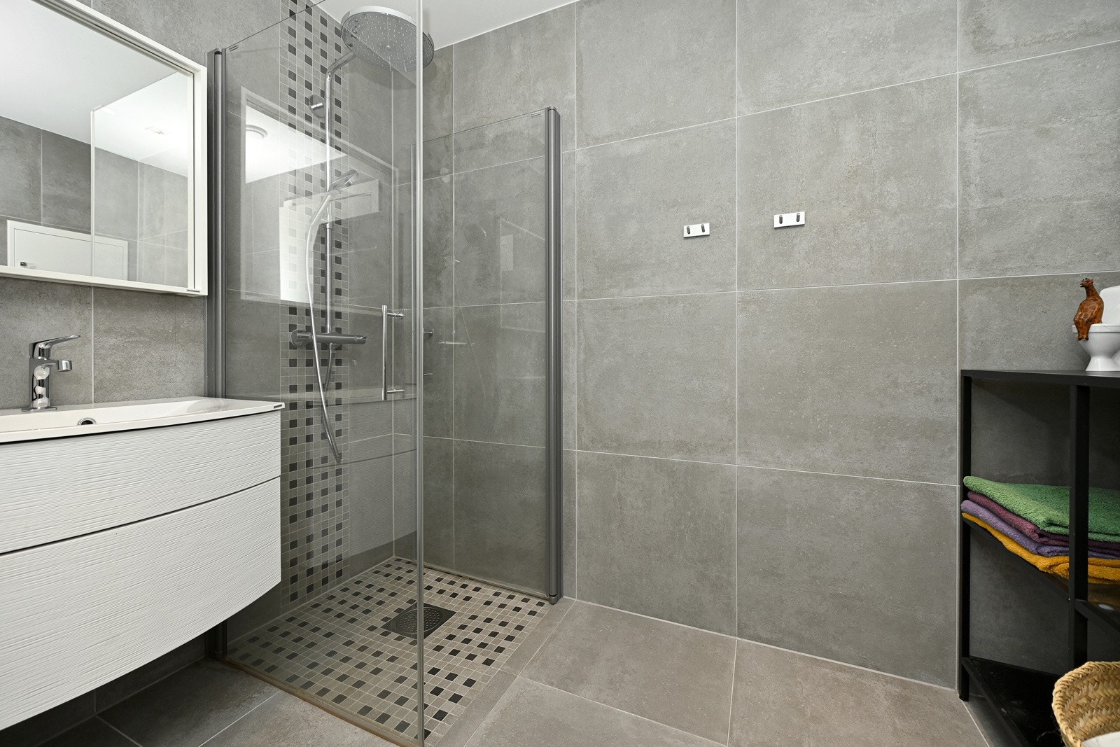 Det andre badet ligger delvis mellom de to minste soverommene. Badet er utstyrt med samme, elegante innredning som hovedbadet, i en smalere utgave, med buede skuffer, heldekkende servant og speil med integrert lys. Galleribilde