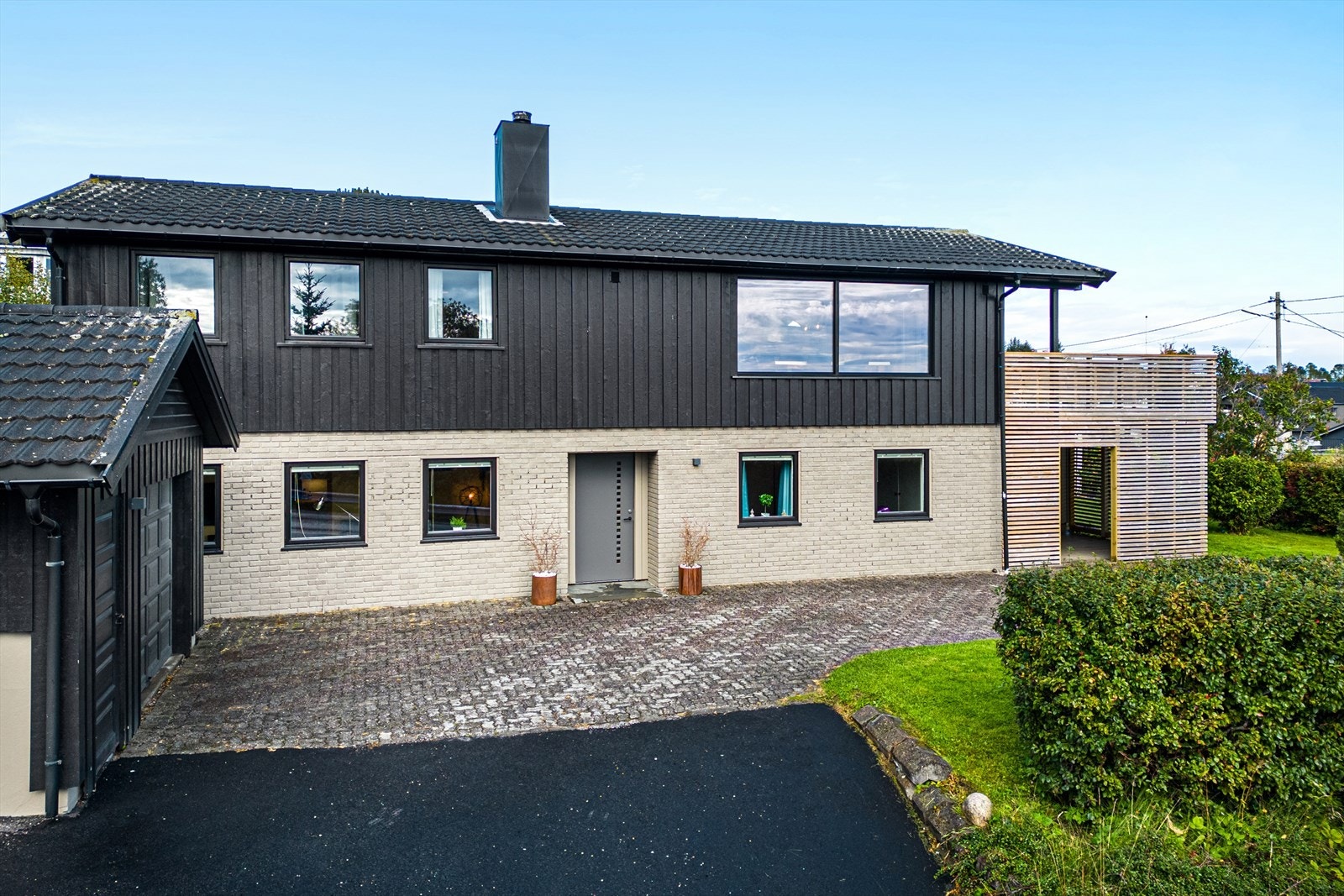 Fasade. Stor gårdsplass med biloppstillingsplass i tillegg til garasje. Galleribilde