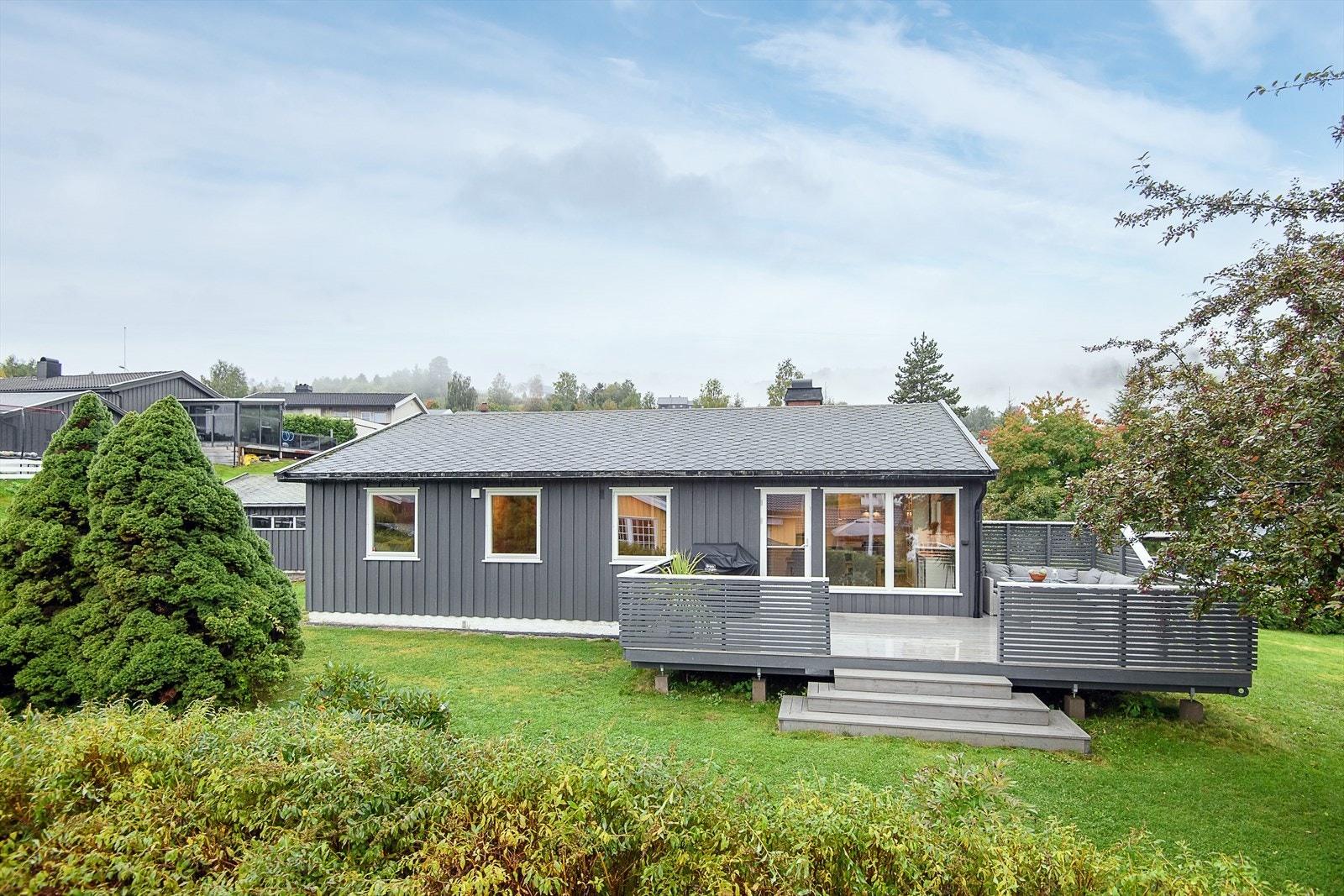 Uteområde med pent opparbeidet med plenareal og diverse beplanting Galleribilde
