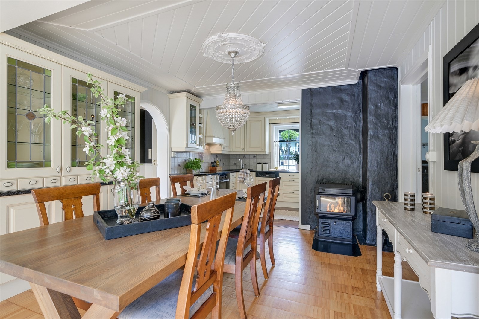 Spisestue med vedovn og kjøkken i bakgrunnen. Galleribilde