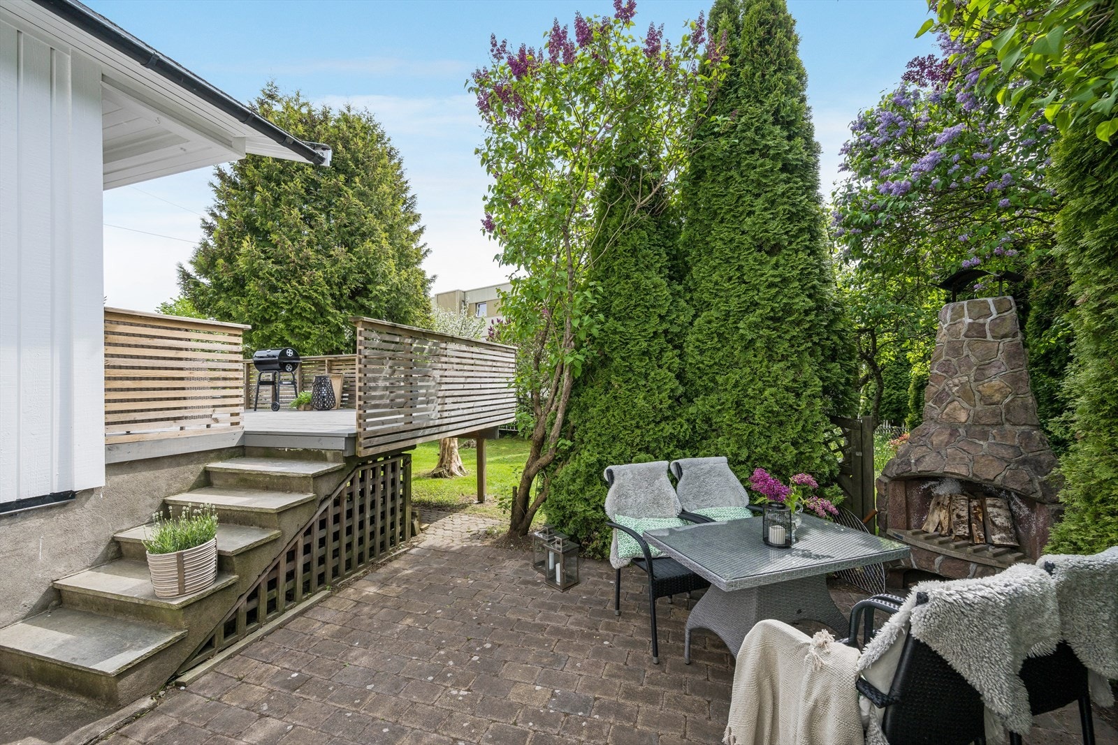 Nedgang fra veranda til skjermet steinsatt uteplass med utepeis. Galleribilde