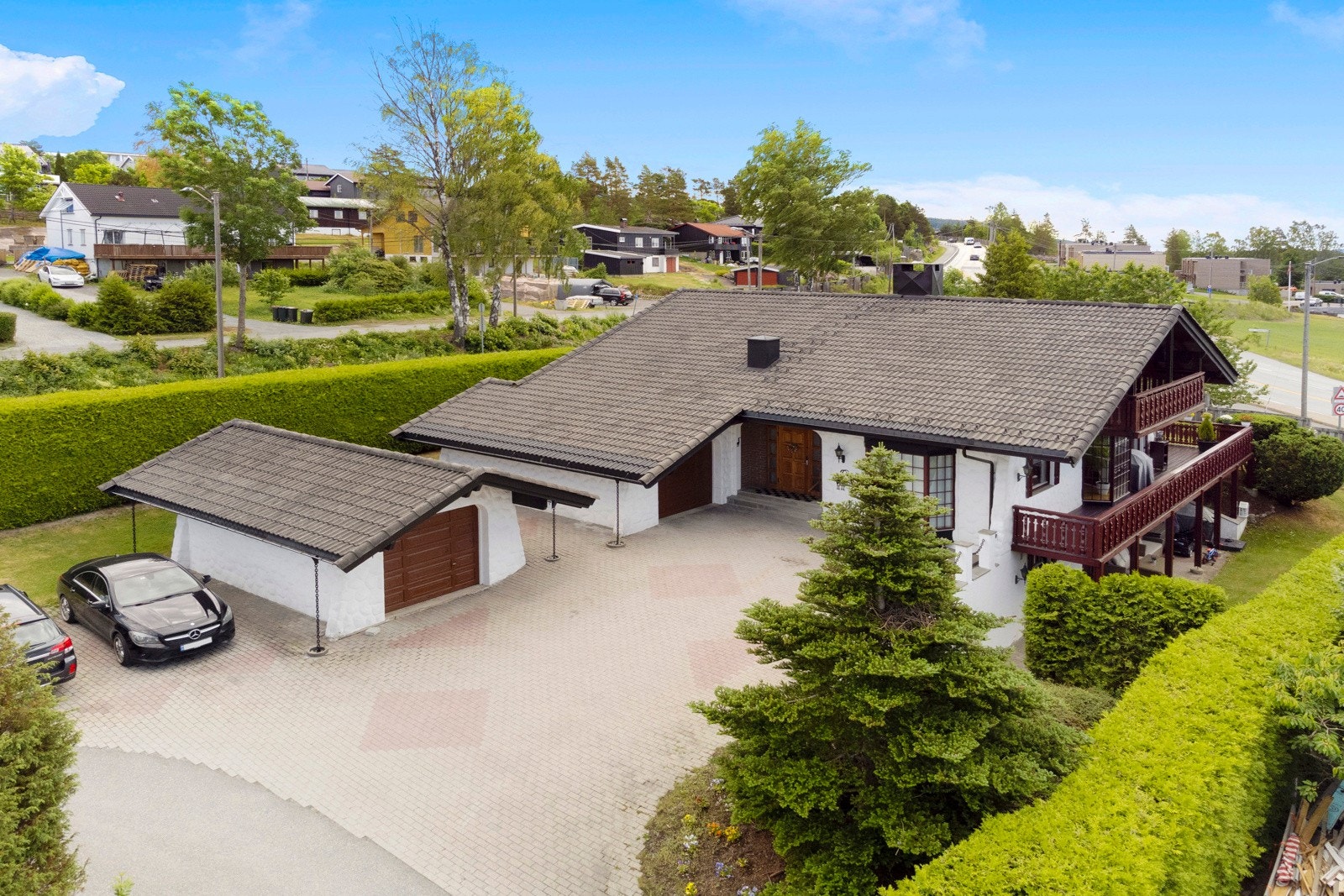 Stor, flott eiendom med to garasjer og stor gårdsplass. Hagen er skjermet av en eviggrønn hekk. Galleribilde