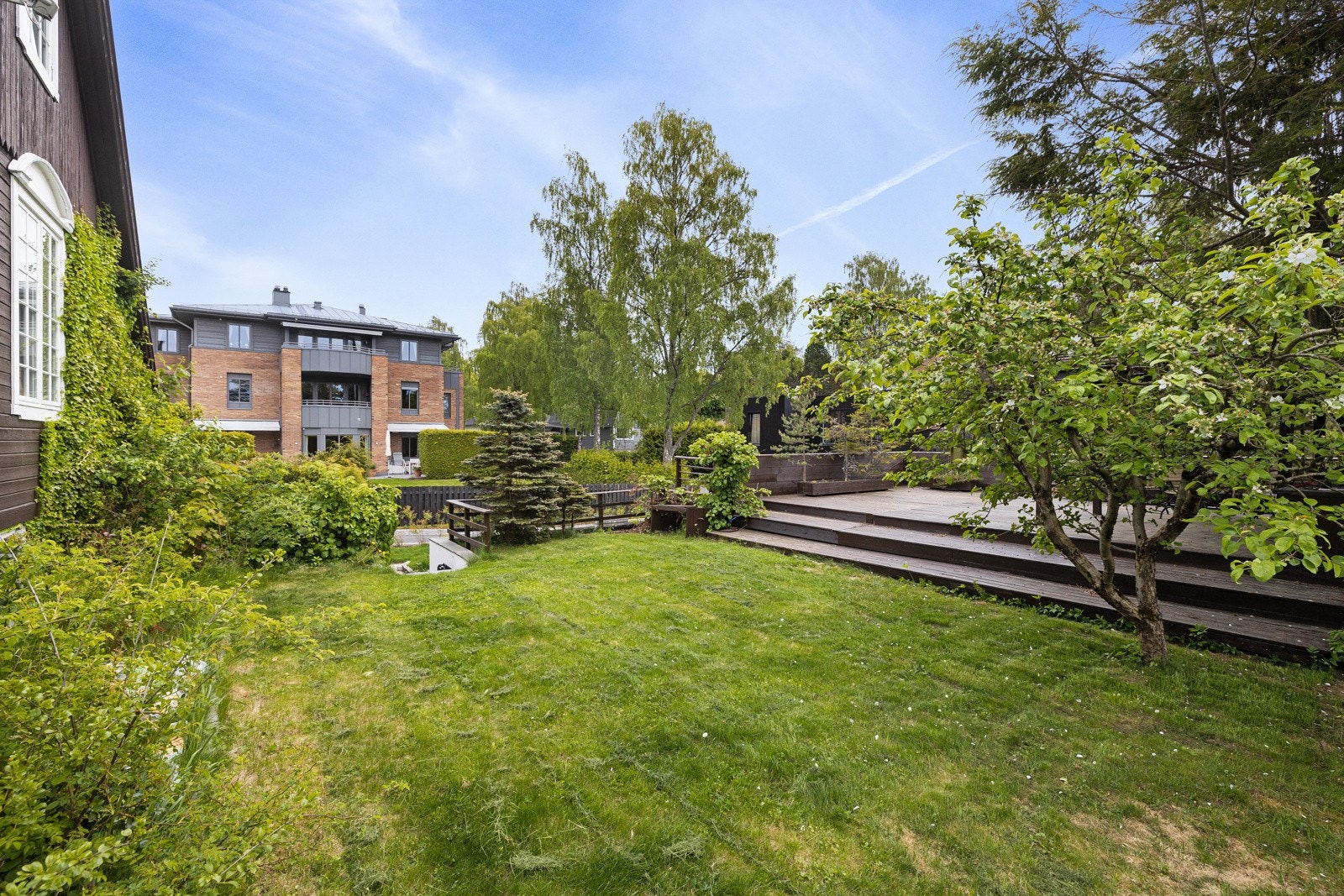 Solrik, flat og bruksvennlig plenhage. Treterrasse med pergola over garasjen. Galleribilde