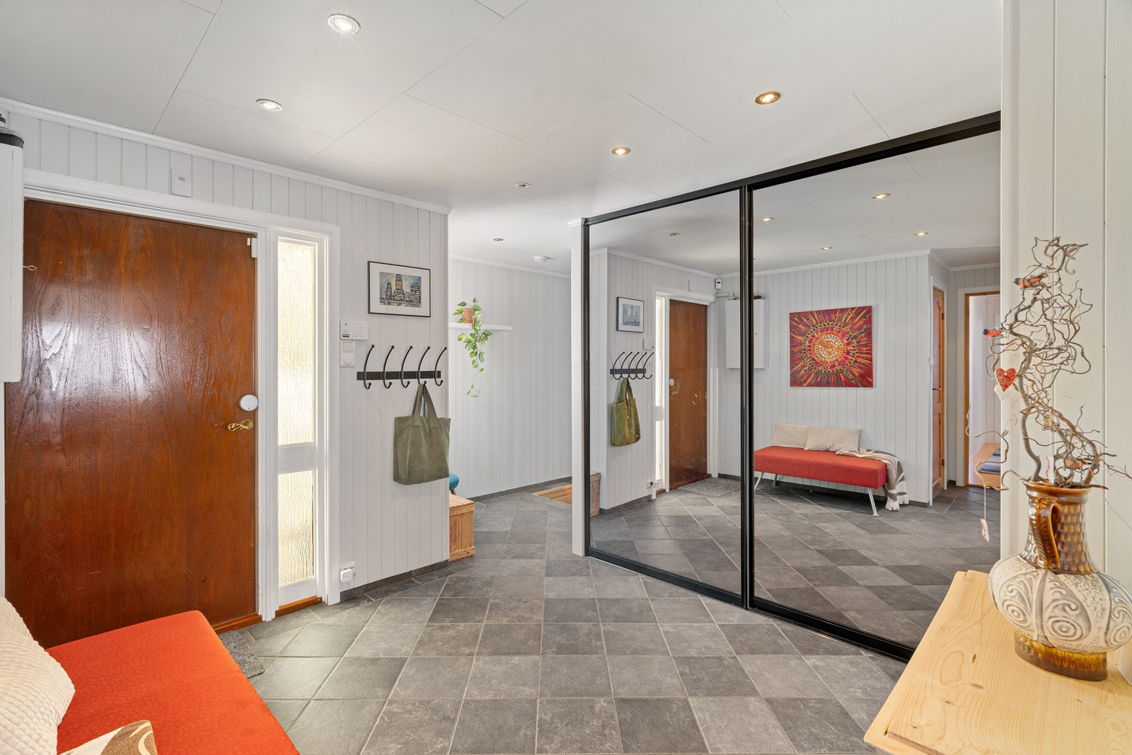 Stor og romslig entré med praktisk skyvedørsgarderobe for oppbevaring.