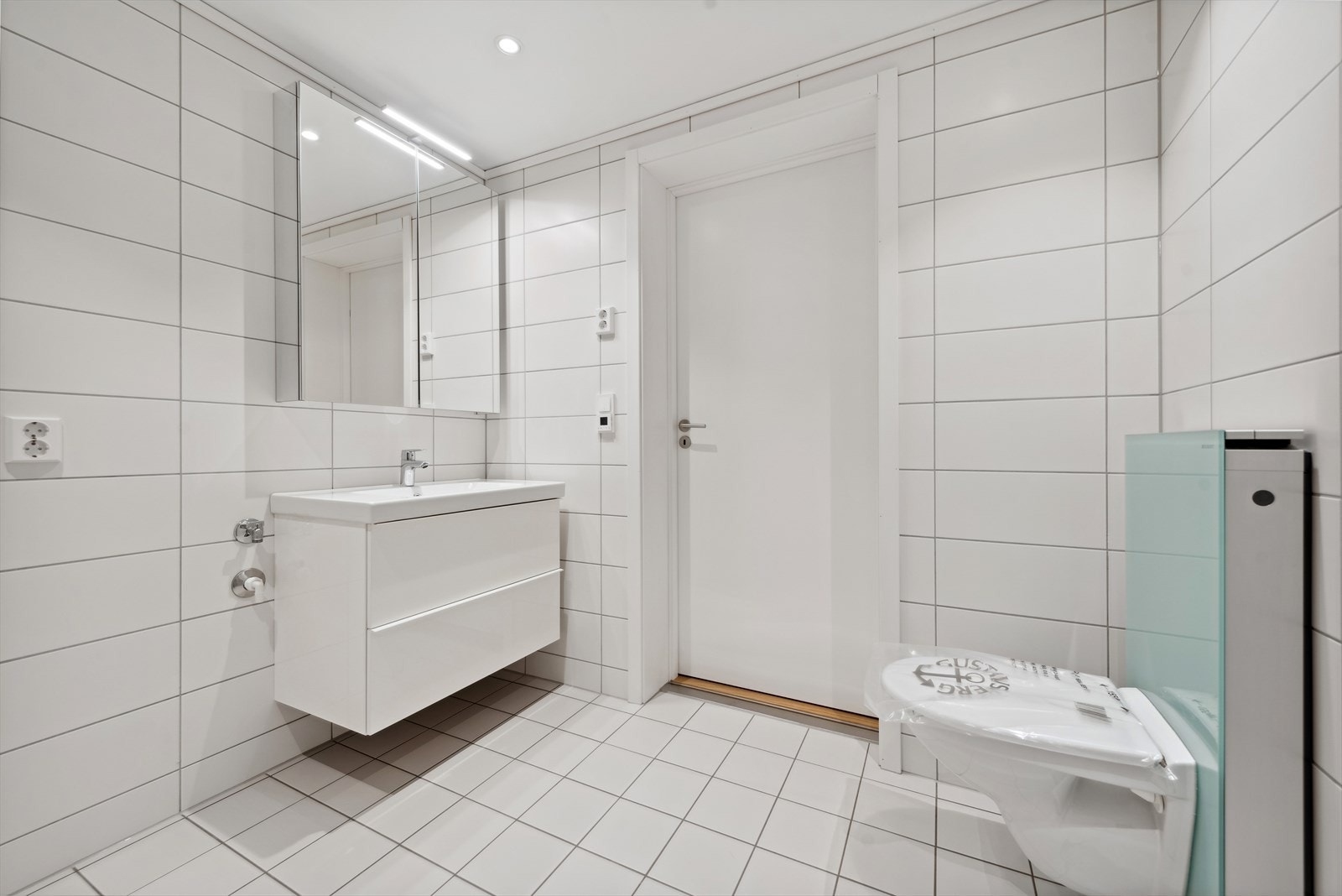 Badet har servant med underskuffer, speilskap og opplegg for vaskemaskin. Galleribilde