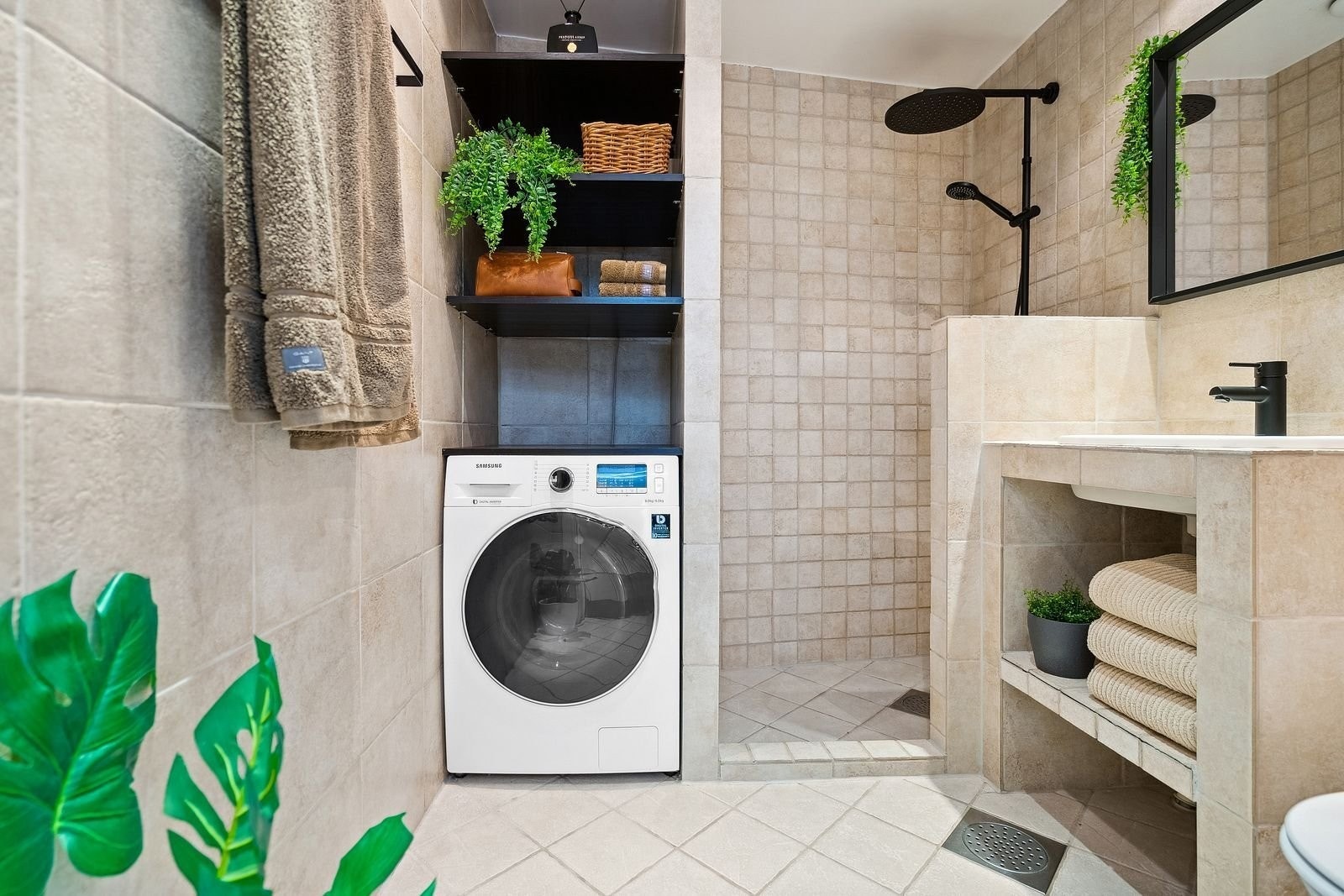 Badet fremstår som moderne, med god plass til vaskemaskin og oppbevaring på hyllene.
Regndusj og svarte, delikate detaljer som harmonerer med trekkene i resten av leiligheten. Galleribilde