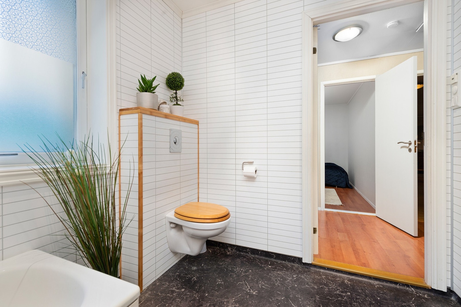 Badet er utstyrt med mekanisk avtrekk, servant, servantskap, badekar og veggmontert wc. Galleribilde