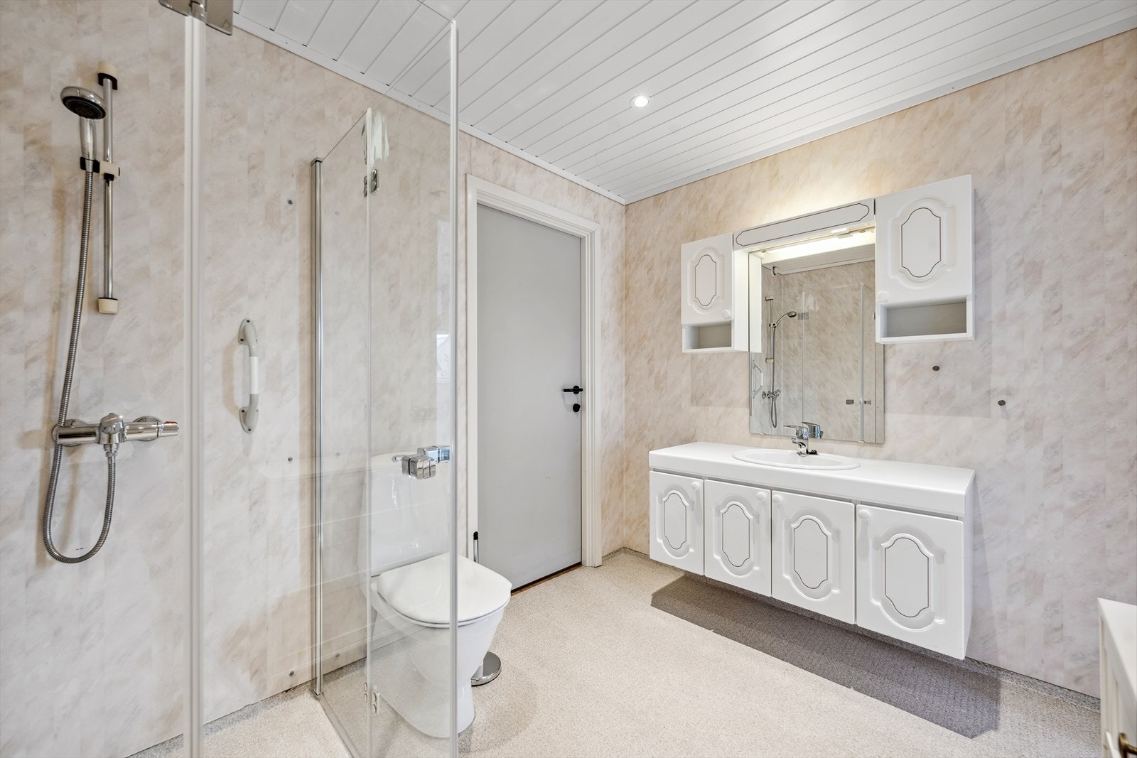 Romslig baderom med adkomst fra entré og soverommet. Badet er gjennomført med vinylbelegg på gulv og vegger med våtromstapet/belegg. Galleribilde