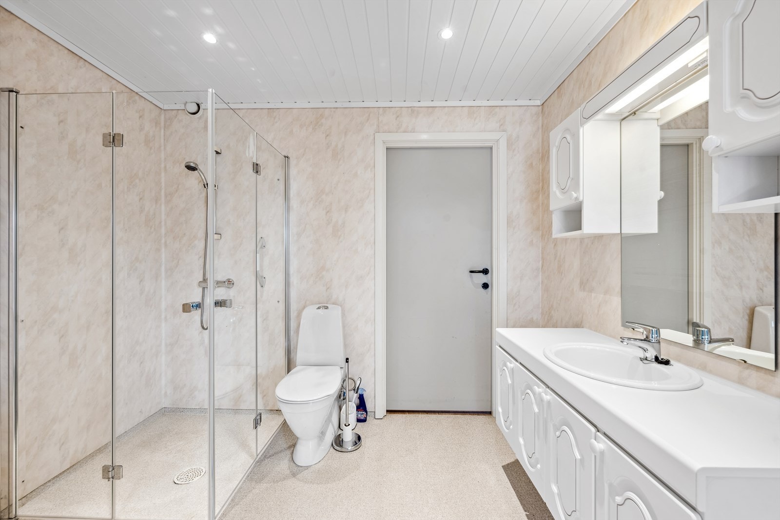 Badet er innredet med baderomsinnredning med skapseksjoner, belyst speil med sideskap og opplegg for vaskemaskin. Det er et romslig dusjhjørne med glassdører og pen spotebelysning i taket. Det er i tillegg nye dusjvegger og toalett. Galleribilde