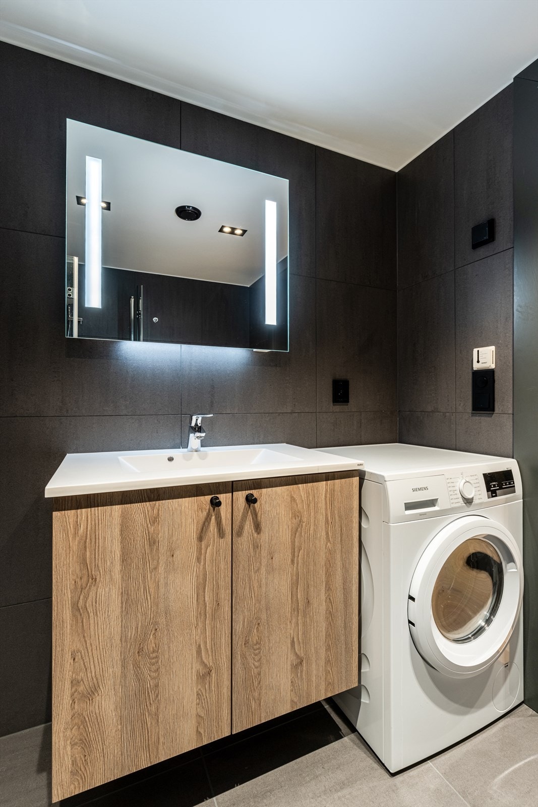 Delikat bad med mørke fliser og lyst baderomsmøbel fra Rotpunkt. Galleribilde