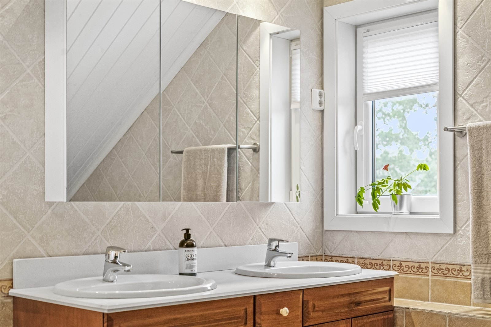 Badet har fliser på gulv og vegger, og her har man toalett, innredning med to servanter og stort badekar. Galleribilde