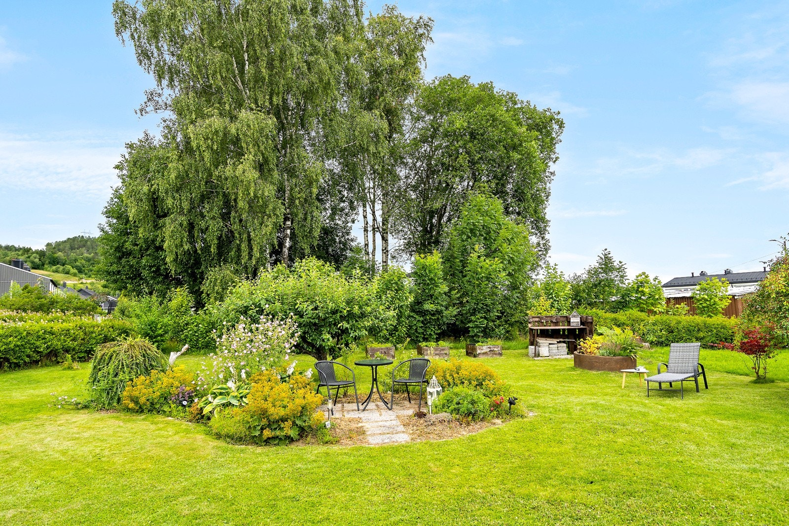 Hagen har en stor anlagt gressplen og er pent opparbeidet med ulike soner med blomsterbed, hekker, diverse beplantning, trær og grønnsakskasser Galleribilde