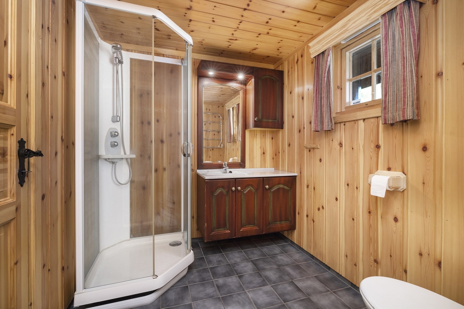 Badet har flislagt gulv, og er innredet med servant, toalett og dusjkabinett. Galleribilde