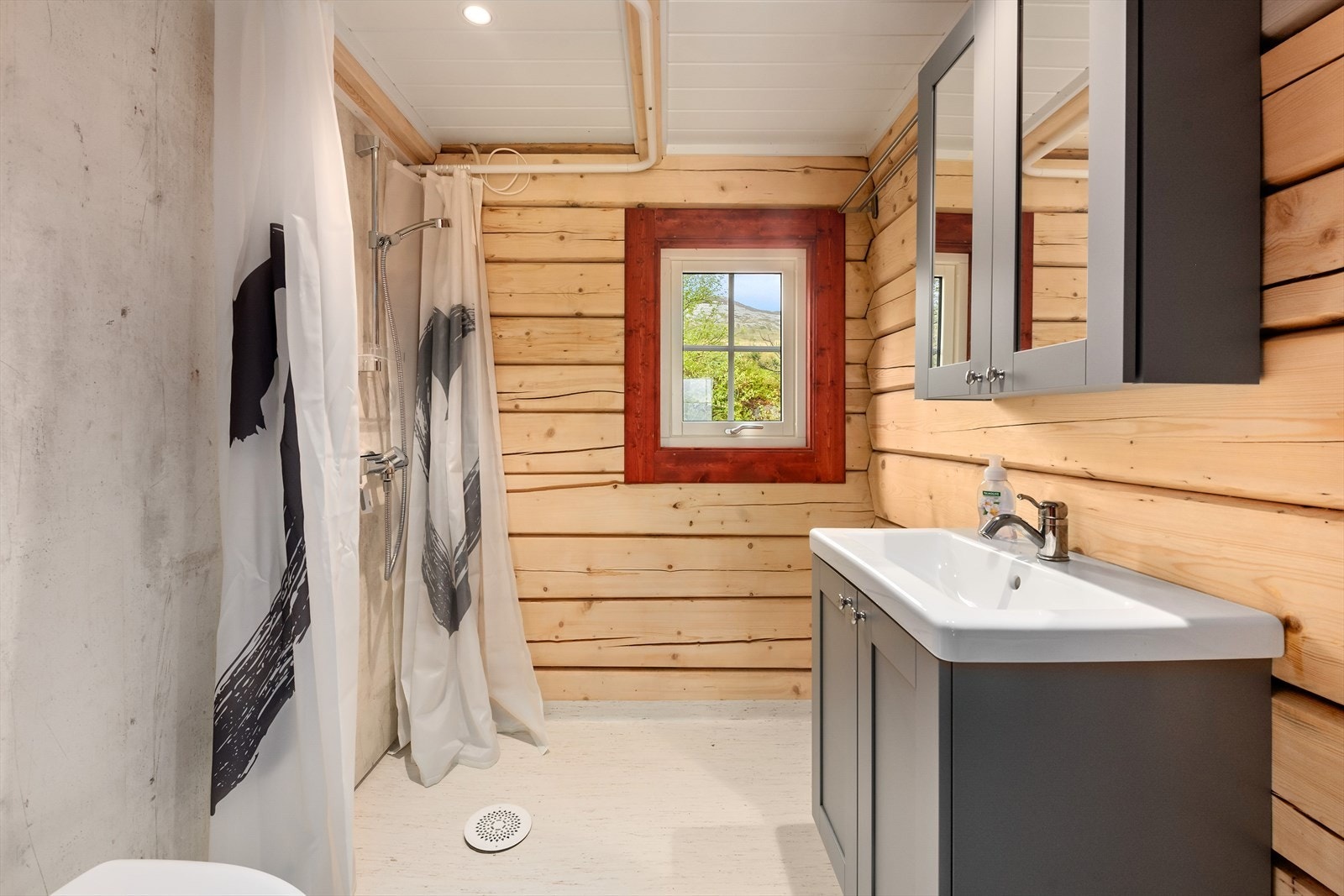 Badet er tøft og litt rustikk med en kombinasjon av tømmer og baderomsplater på veggene. Det er betonggulv med vinylbelegg med vannbåren varme i gulvet. Galleribilde