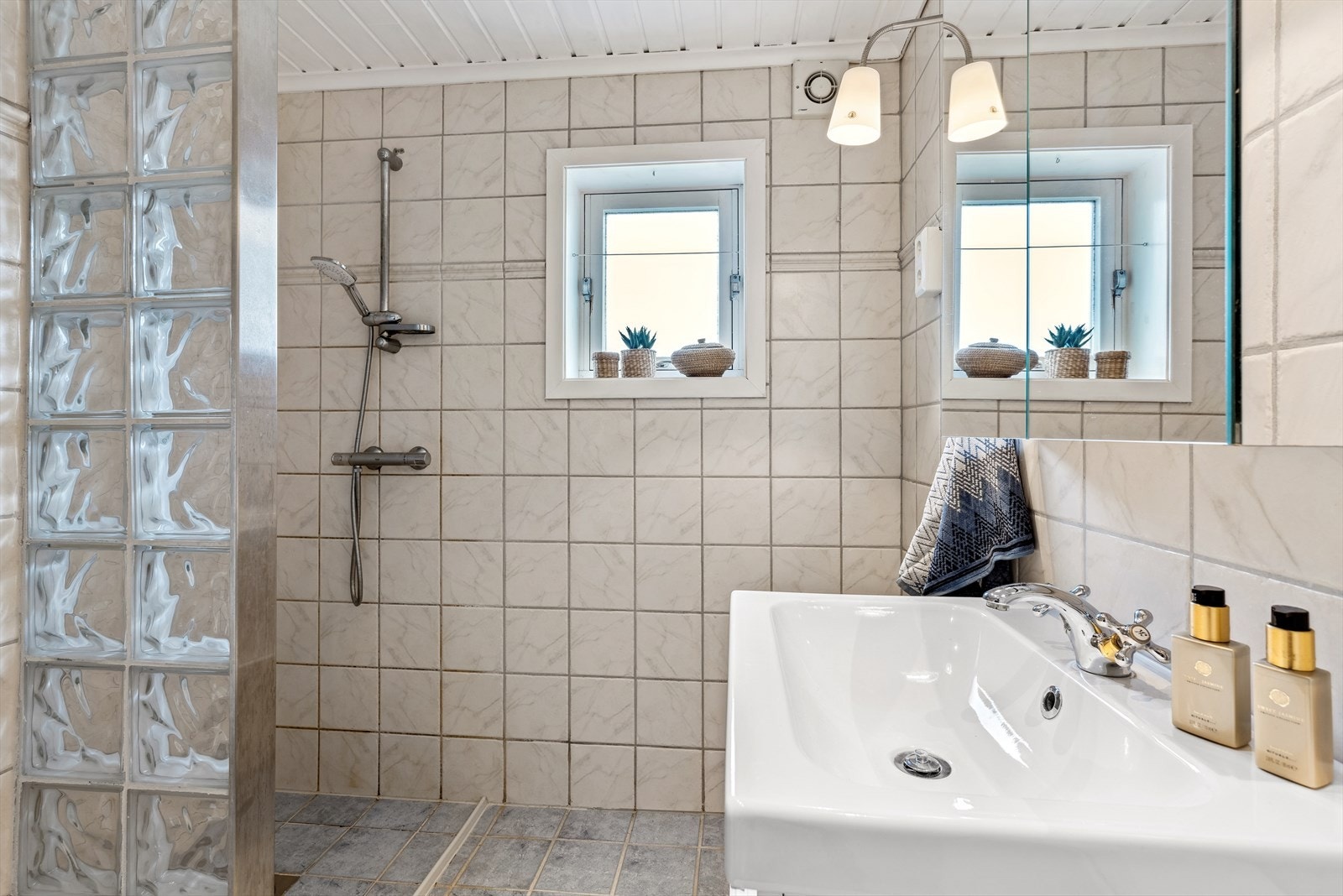 Bad innredet med dusj, speil- og servantskap, ett høyskap med speil og wc. Galleribilde