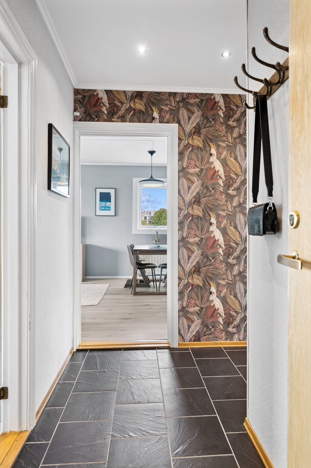 Lys og innbydende entré med praktiske fliser på gulv og plass til å henge fra seg yttertøy og sette fra seg sko. Galleribilde