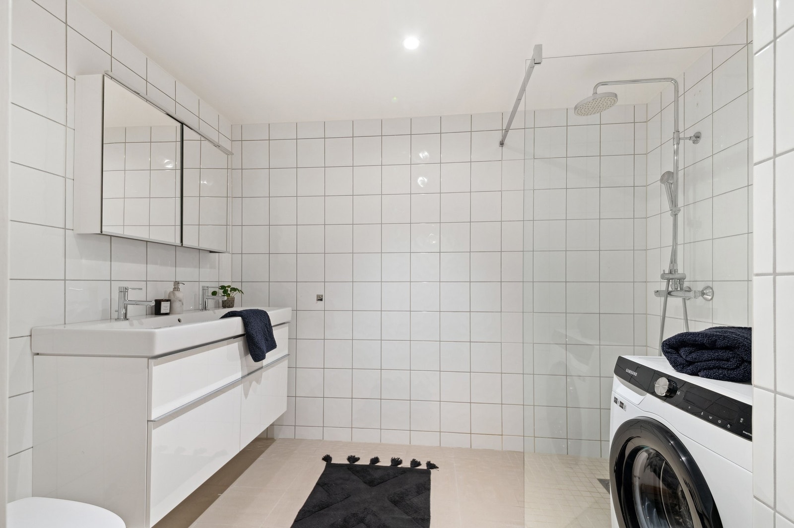 Tiltalende bad med dobbel vask, innredning med overskap og skuffer, vaskemaskin og plass til tørketrommel. Galleribilde