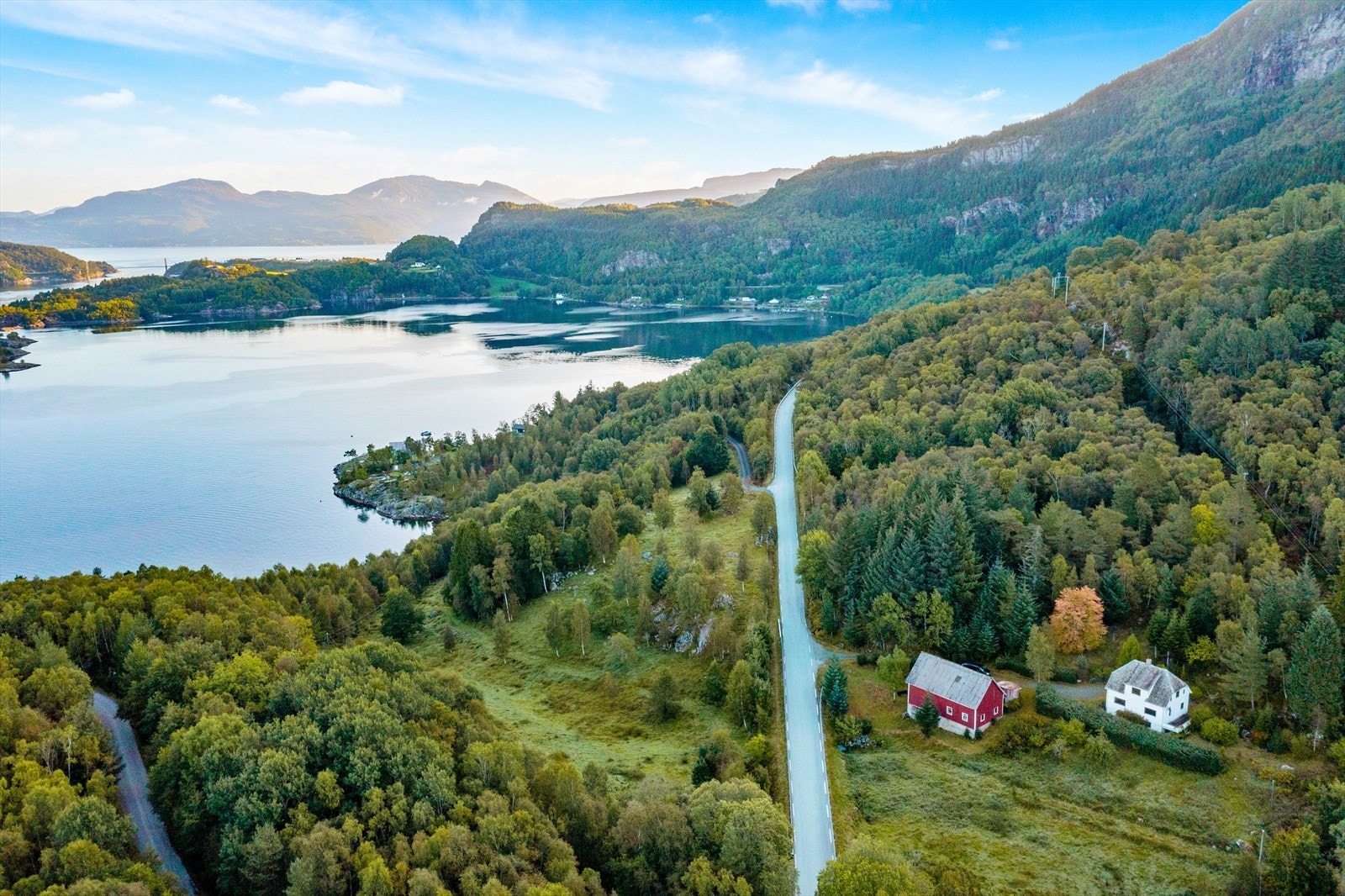 Flott oversiktsbilde av store deler av eiendommen både på nedsiden mot sjø og på oppsiden av veien mot Hjelmeland. Avkjørselen fra riksveien liggr på eiendommen og er anlagt ned til sjøen hvor eiendommen har strandlinje. Galleribilde