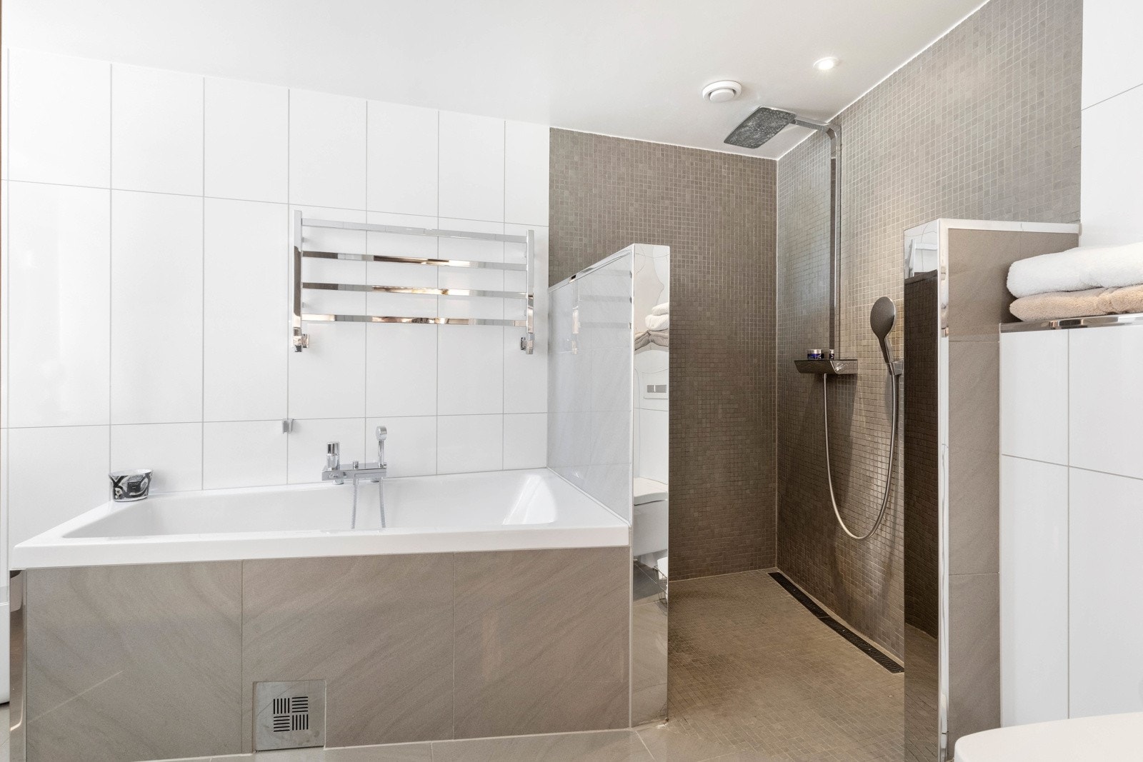 Flislagt bad som inneholder badekar, dusjhjørne, wc og servant Galleribilde