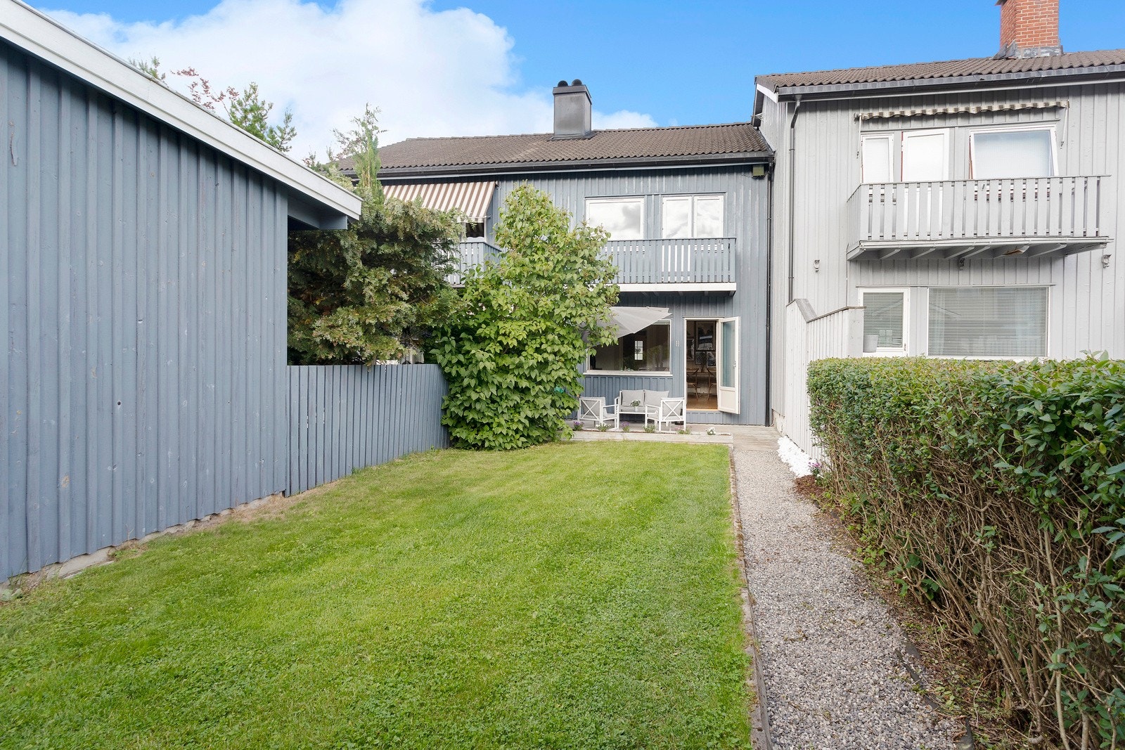 Fra carporten kommer man inn i hagen som er opparbeidet med plen og gruset gangsti frem til terrassen. Galleribilde