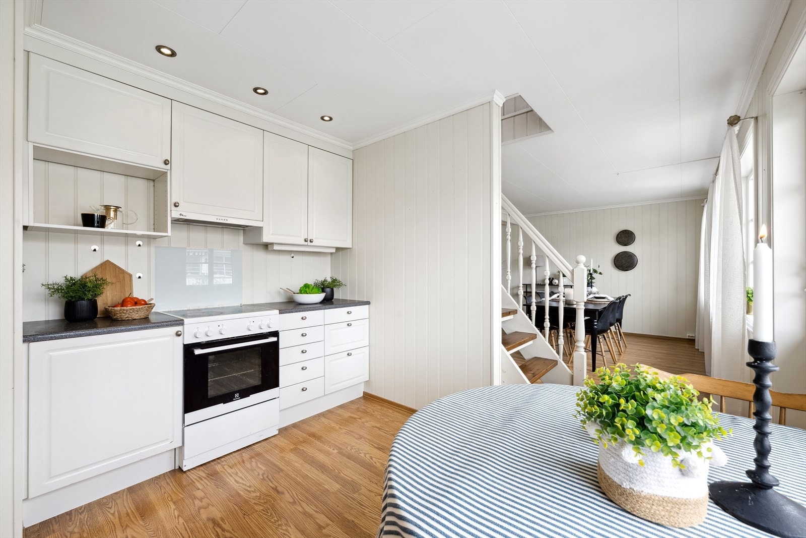 Kjøkkeninnredning i malt/lakkert utførelse med profilerte fronter. Laminerte benkeplater med rustfri oppvaskbenk og kummer. Ventilator. Galleribilde
