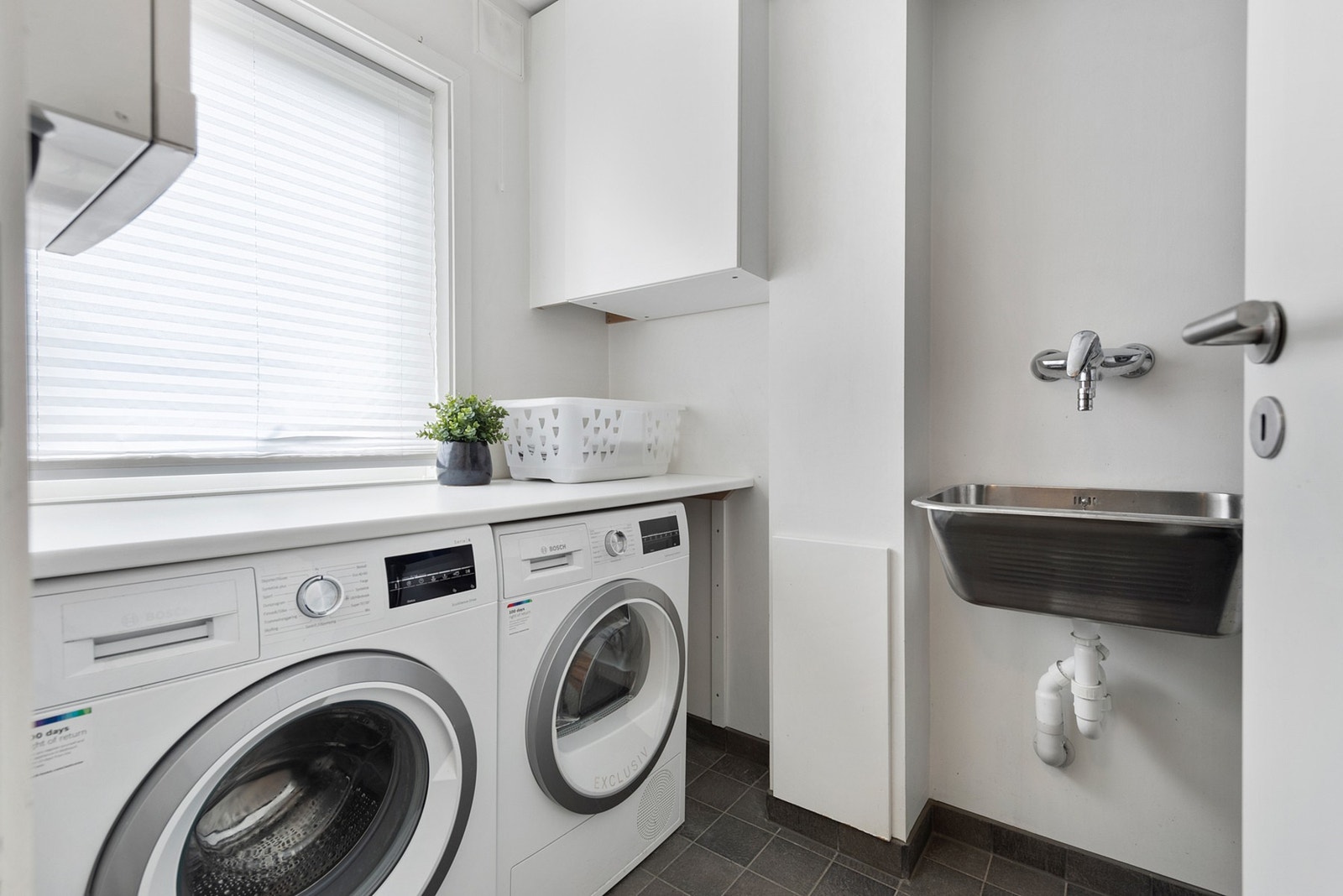 Praktisk, flislagt vaskerom med opplegg for vaskemaskin og tørketrommel, vaskekum og god benkeplass. Galleribilde