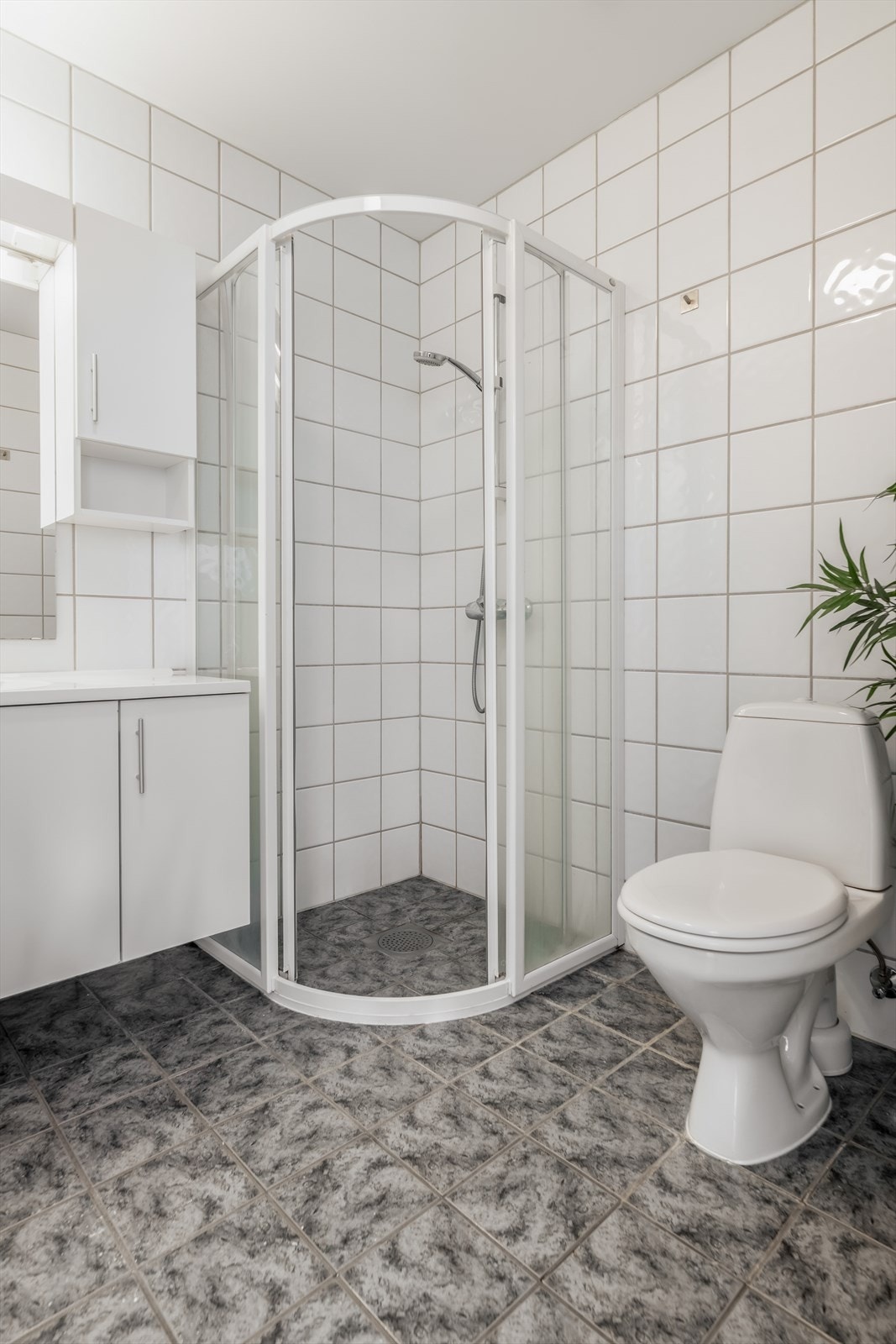 Badet inneholder dusjhjørne, toalett og servantinnredning med underskap, overskap, speil og lys samt el-stikk. Galleribilde