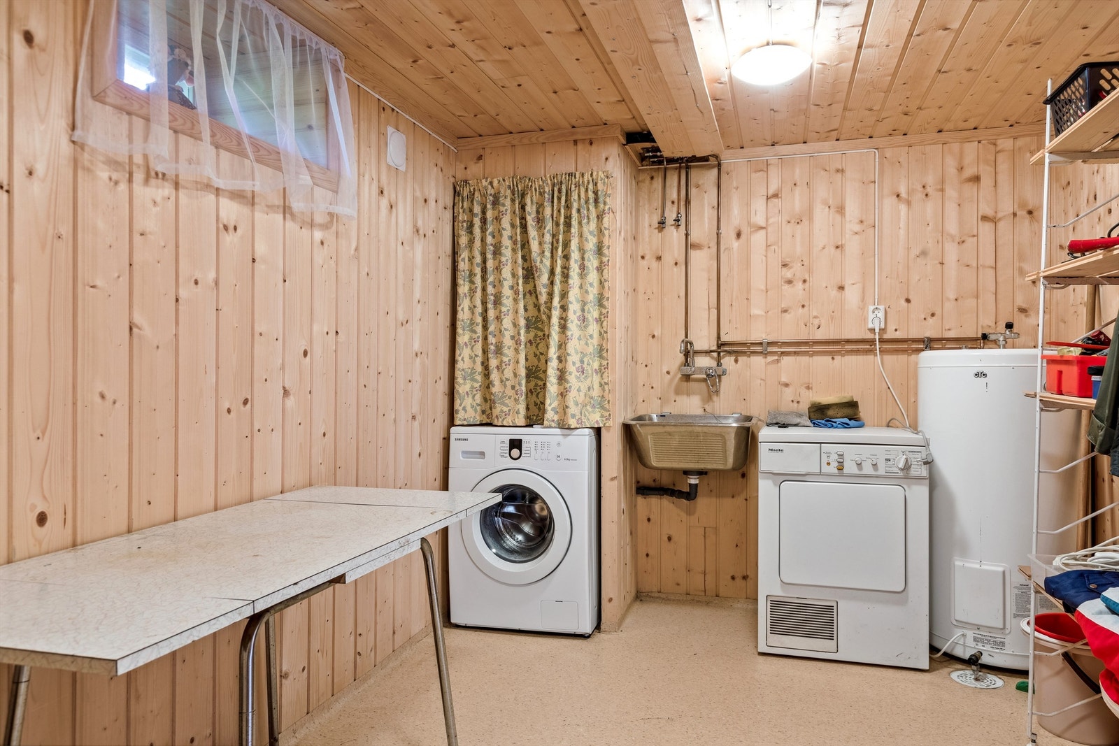 Vaskerom i kjelleren med varmtvannsbereder, vegghengt vaskekum og opplegg for vaskemaskin. Rommet er vurdert til TG3. Galleribilde