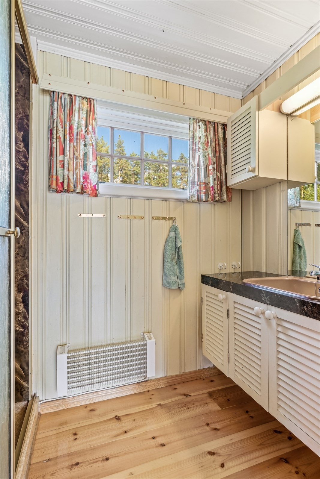 Badet er utstyrt med servantinnredning, overskap og vegghengt dusj i nisje med skyvedør Galleribilde