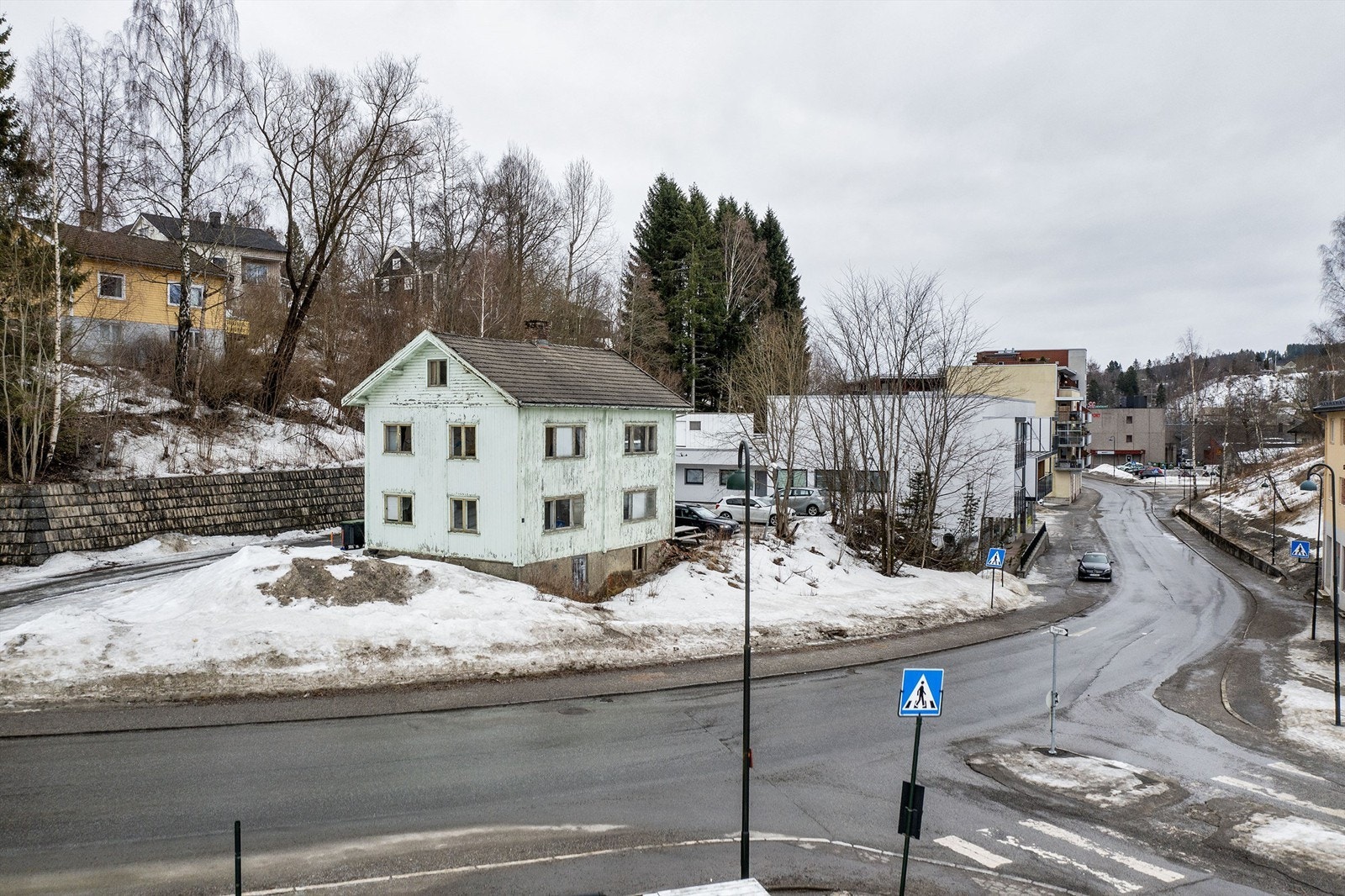 Lett skrånet tomt opparbeidet med grus/asfalt og beplantning. Galleribilde