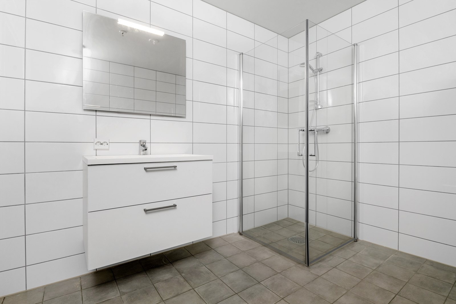 Helfliset bad. Servant med nedfelt vask, vegghengt toalett og dusjhjørne. Galleribilde