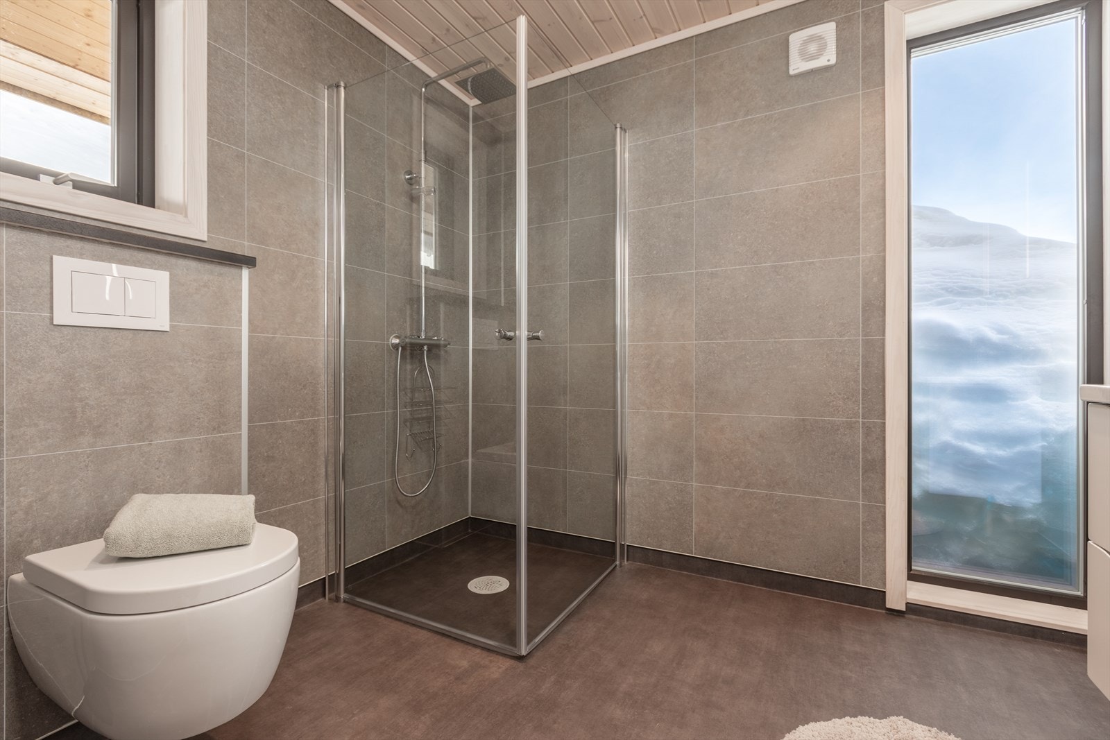 Badet er utstyrt med baderomsmøbel med enkel servant, dusjhjørne og vegghengt toalett. Galleribilde