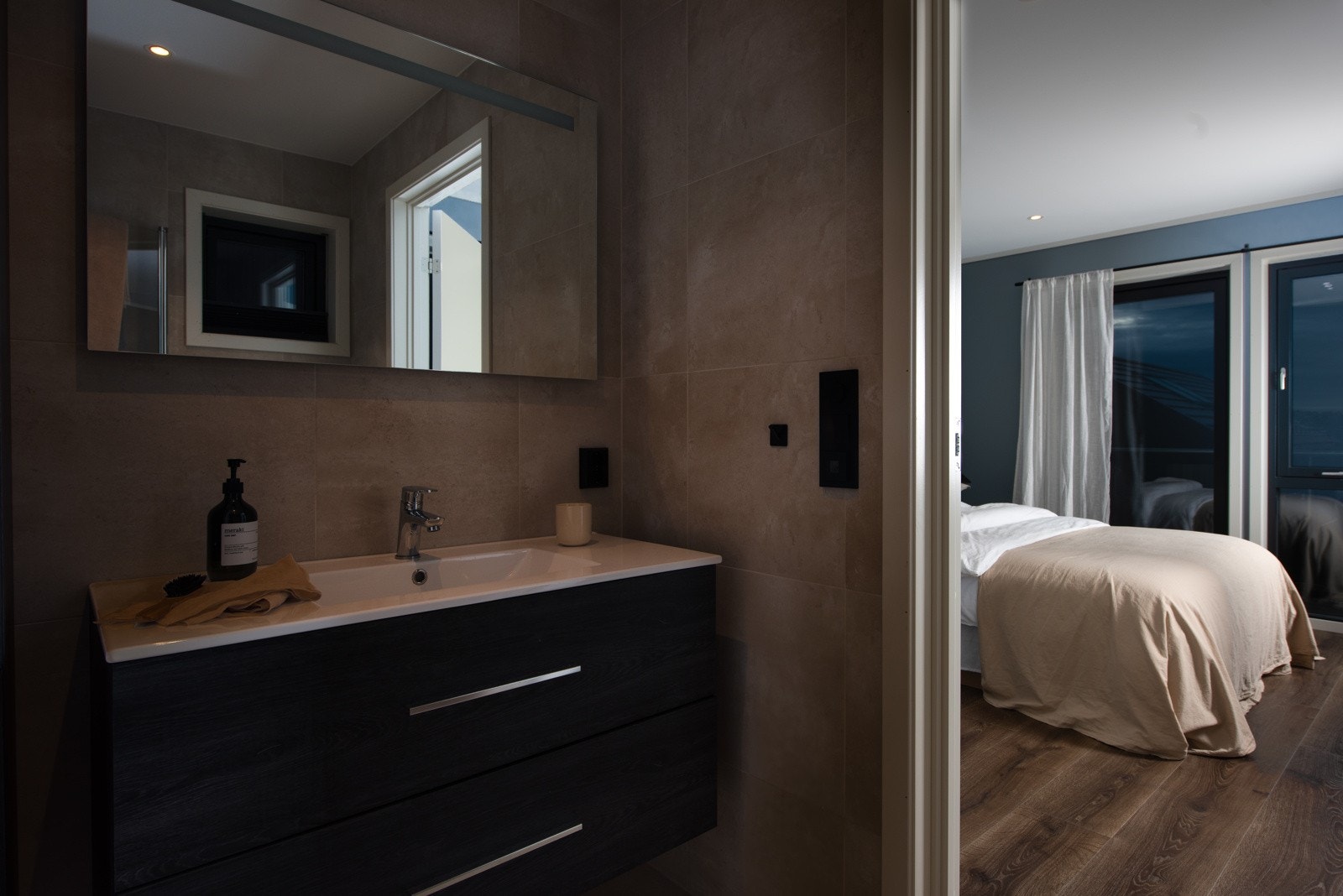 Badet tilhørende hovedsoverommet har speil med integrert LED-belysning, heldekkende servant på mørkt skuffemøblement og et matchende høyskap. Galleribilde