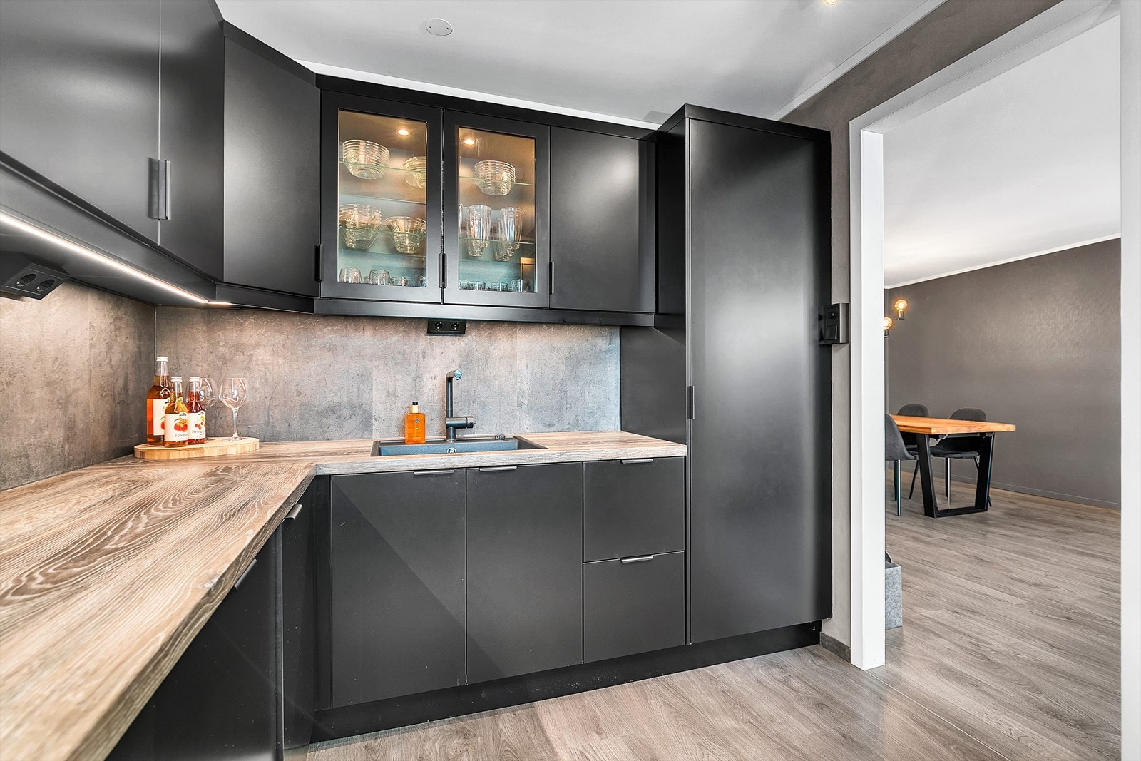 Kjøkkenet er utstyrt med oppvaskmaskin, stekeovn, platetopp, helintegrert kjøl- og fryseskap. Det er LED-list under overskap og belysning i glasskap. Galleribilde