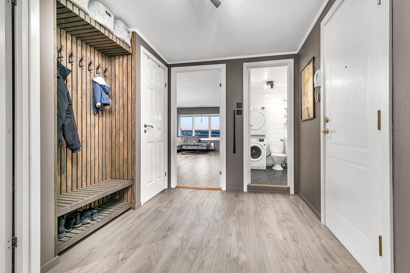 Delikat spilevegg med praktisk løsninger for oppbevaring og oppheng av yttertøy. Galleribilde