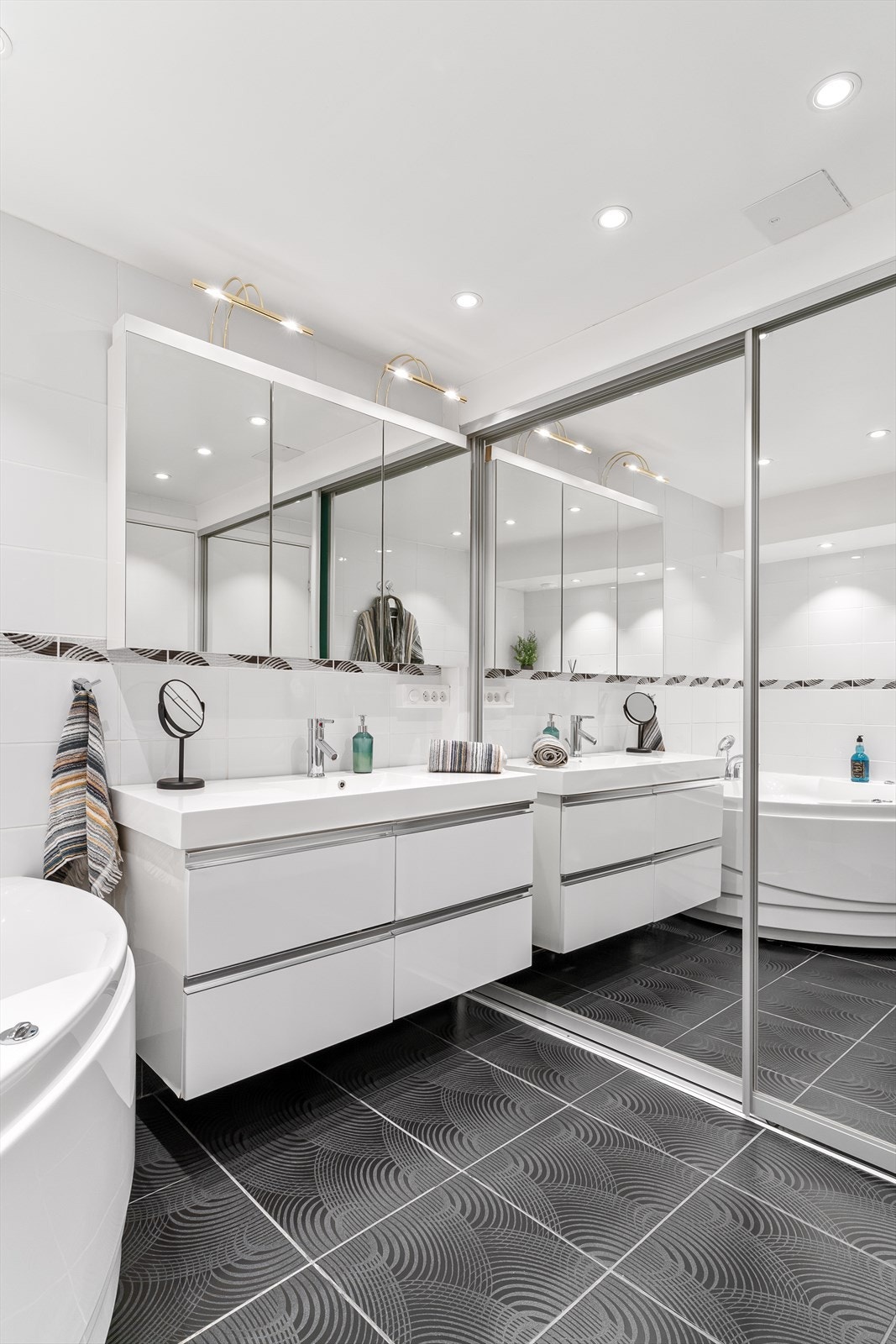 Badet har en praktisk løsning med oppbevaring og opplegg for vaskemaskin/tørketrommel gjemt bak skyvedører Galleribilde