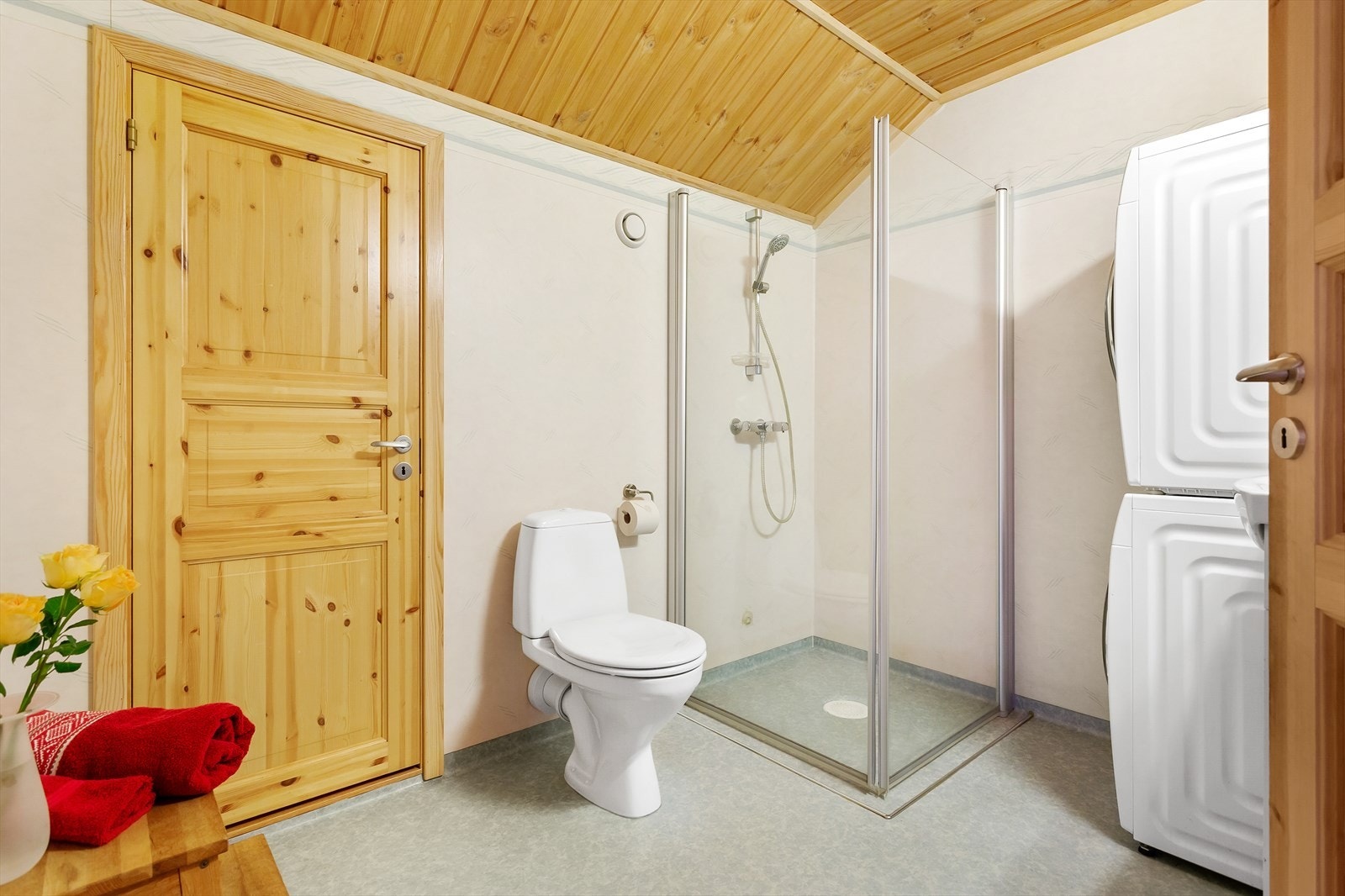 Bad med gulvbelegg på gulv og tapetserte vegger og opplegg for vaskemaskin og tørketrommel. Galleribilde