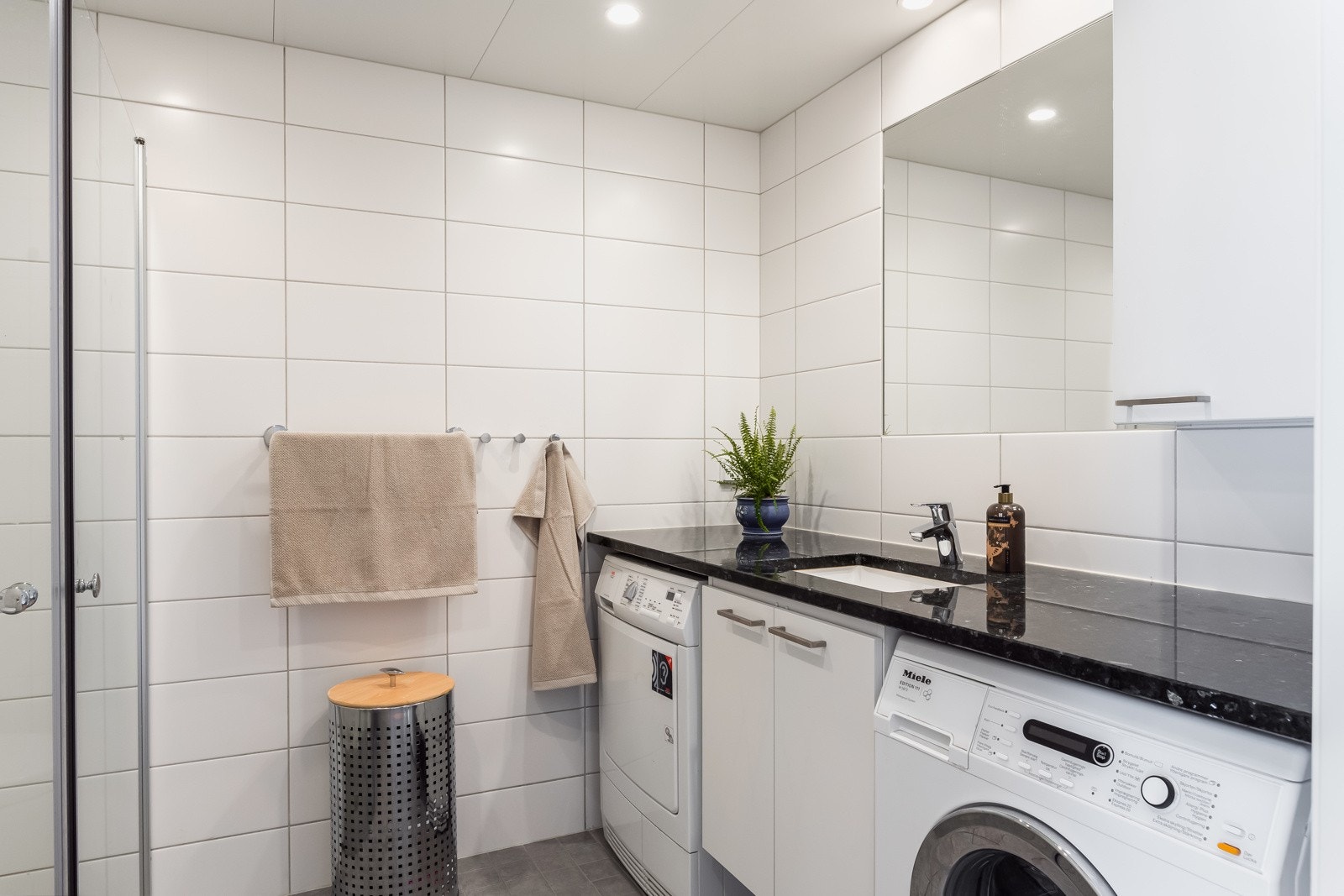 Badet inneholder dusjvegger av glass, vegghengt toalett, innredning med servant, samt opplegg for vaskemaskin og tørketrommel. Ingen tegn til fukt eller skader, TG 1 ifølge takstmann. Galleribilde
