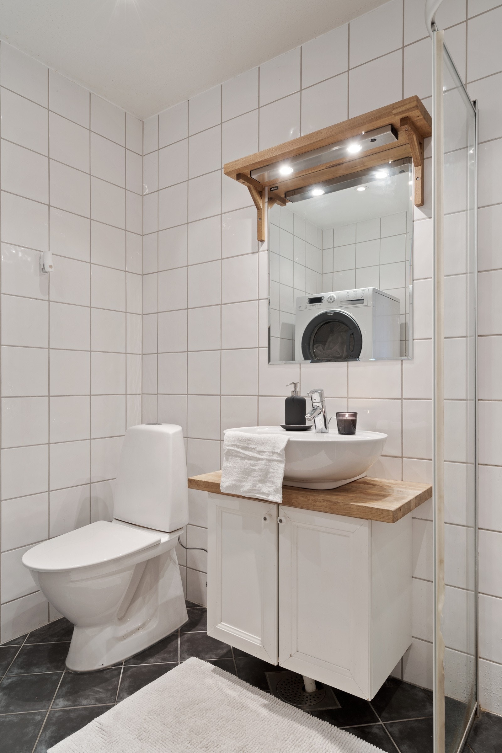 Badet er utstyrt med toalett, servaninnredning, dusjhjørne og opplegg for vaskemaskin. Galleribilde