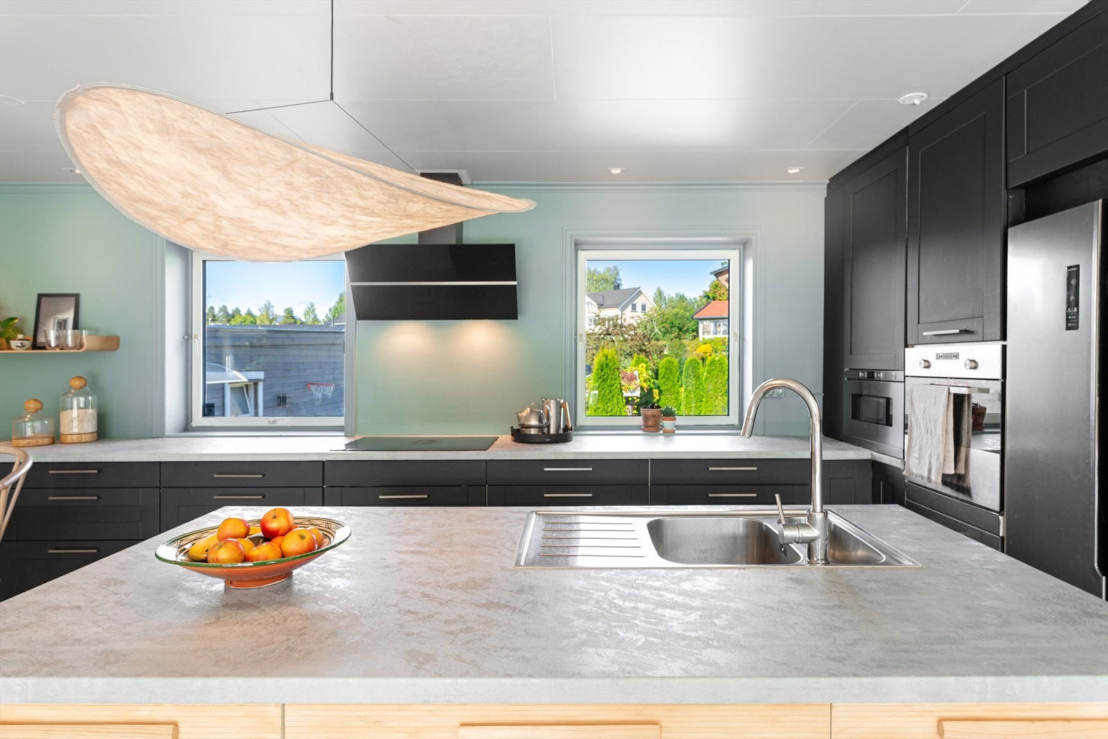 Delikat kjøkken med mørk profilert innredning og stor øy med nedfelt oppvaskkum. Galleribilde