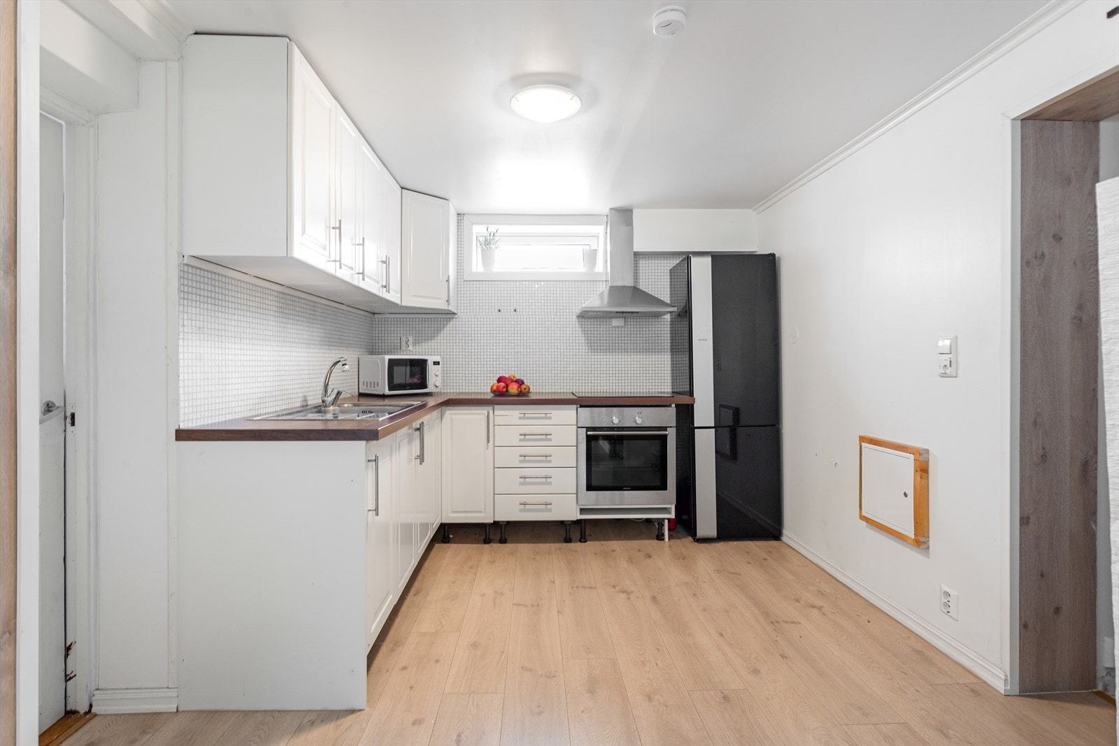 Lyst kjøkken med fliser mellom over og underskap og laminert benkeplate med nedfelt oppvaskkum med 1-greps blandebatteri. Det er montert en integrert komfyr og nedfelt platetopp og det er tilkoblet en ventilator over kokeplass. Galleribilde