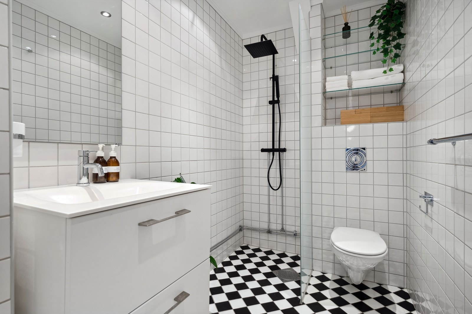 Badet i 1. etasje har flislagt gulv med behagelig gulvvarme og flislagte veggoverflater. Det er vegghengt toalett og dusjhjørne. Nytt dusjarmatur i 2023. Galleribilde