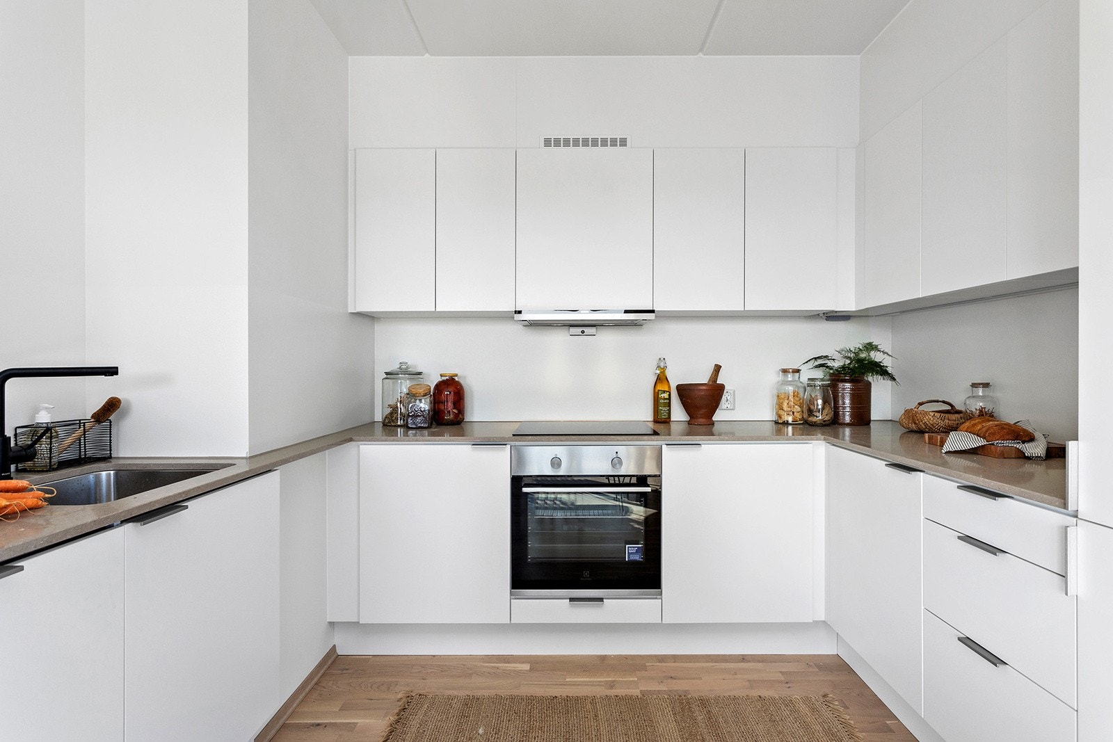 Flott HTH-kjøkken med integrerte hvitevarer (stekeovn, induksjonstopp, kjøl/frys, oppvaskmaskin) og ventilatorhette. Galleribilde