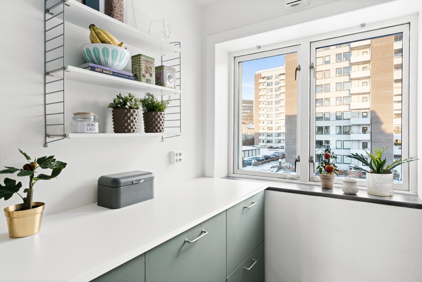 Over deler av benken er det hvite metrofliser, og over kokesonen er det installert en ventilator. Av hvitevarer har kjøkkenet komfyr, integrert oppvaskmaskin og en frittstående kjøl/frys i egen nisje. Galleribilde