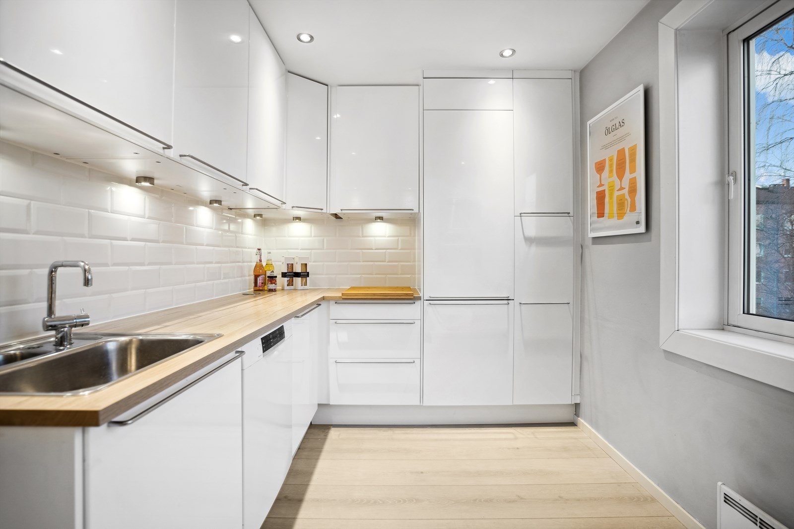 Moderne Ikea kjøkkeninnredning med glatte, høyglans fronter. Laminat benkeplate med nedfelt kum i rustfritt stål. Galleribilde