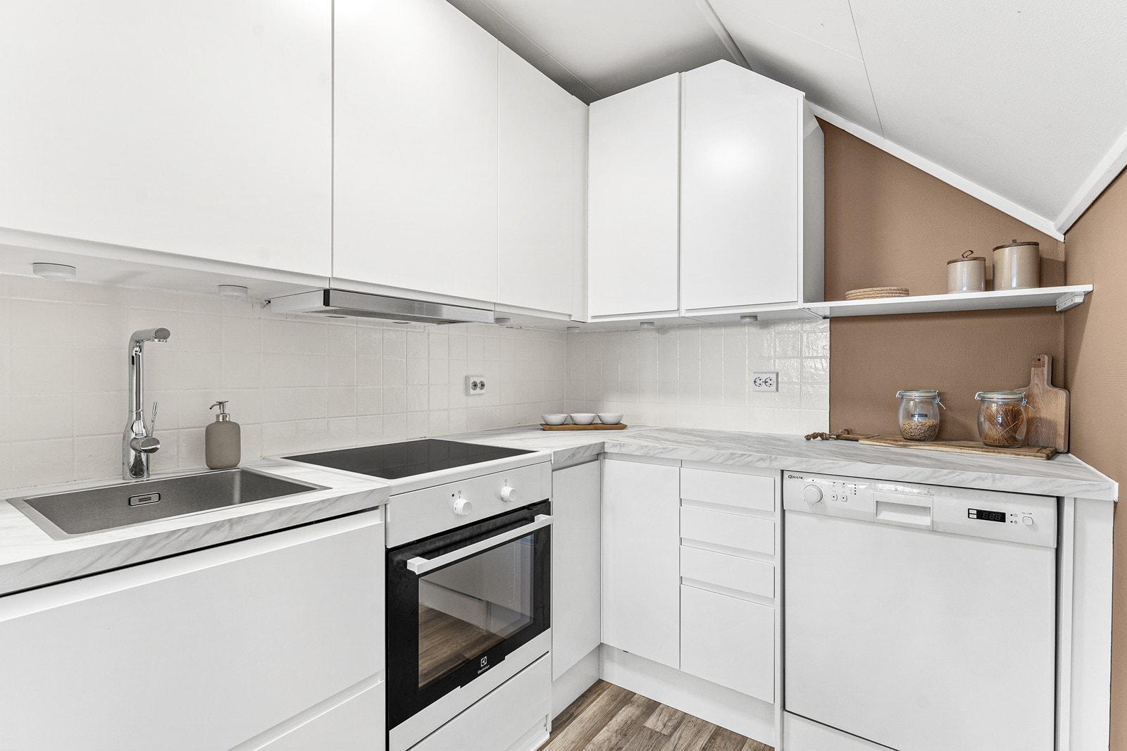 Kjøkkenet holder god kvalitet med glatte fronter i hvit utførelse, laminert benkeplate og nedfelt vask i stål. Galleribilde