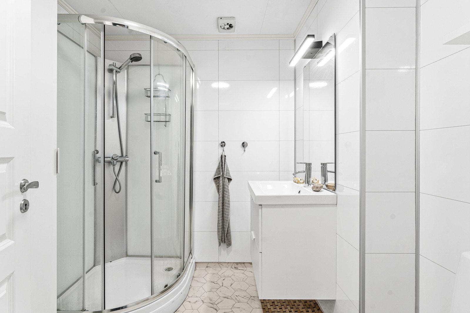 Bad/vaskerom fremstår som moderne og lekkert med gulvbelegg med varmekabler, baderomsplater på vegger og himlingsplater i taket. Galleribilde