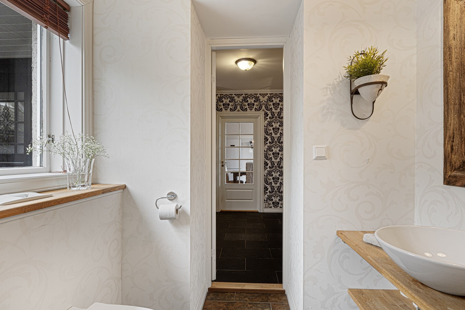 Flott gjestetoalett med fliser på gulv og lyse tapeter på vegger (2007) Galleribilde