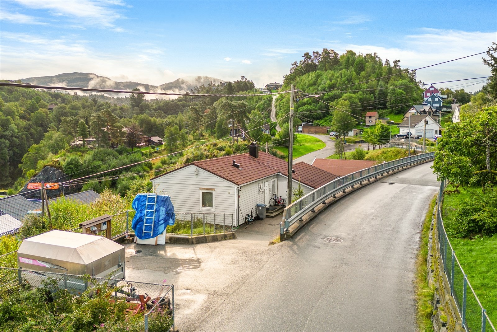 Tomten er opparbeidet med asfaltert plass på oppsiden av huset. Galleribilde