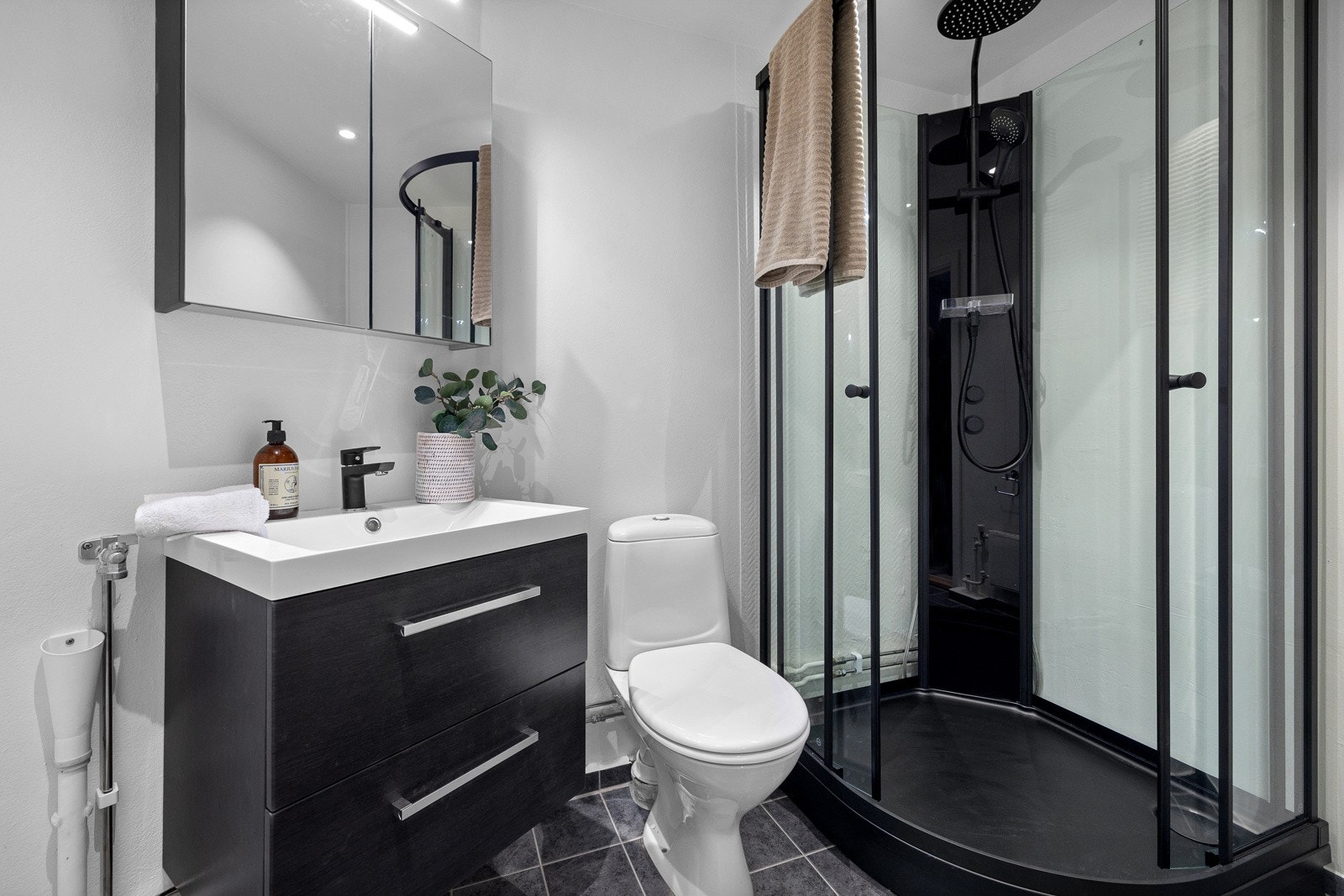 Tiltalende baderom, pusset opp i 2023 med ny servant med skuffer for oppbevaring, romslig dusj og speil med belysning. Oppplegg for vaskemaskin. Galleribilde